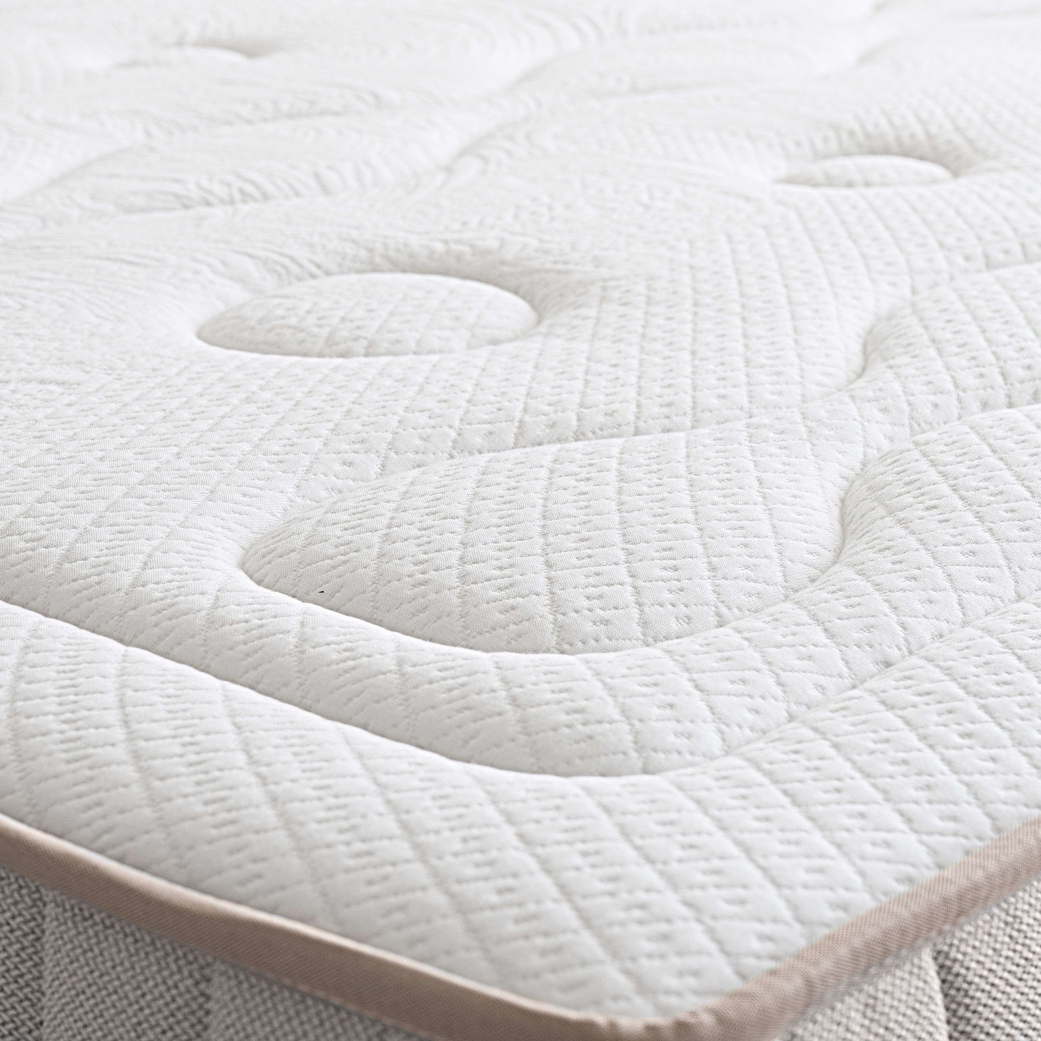 Un primer plano de un colchón blanco acolchado con borde beige.