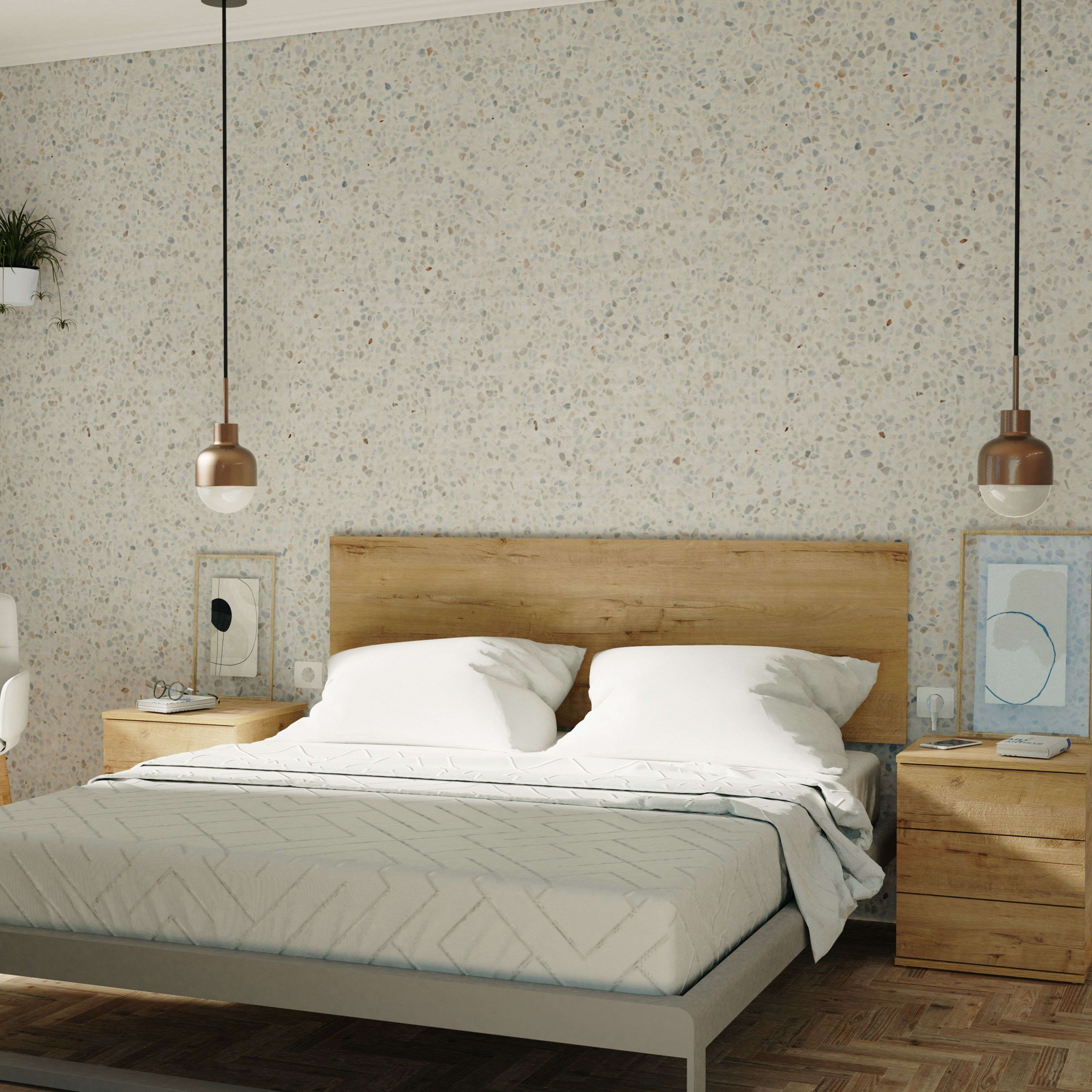 Un dormitorio con cama doble, mesitas de noche de madera y pared de terrazo.