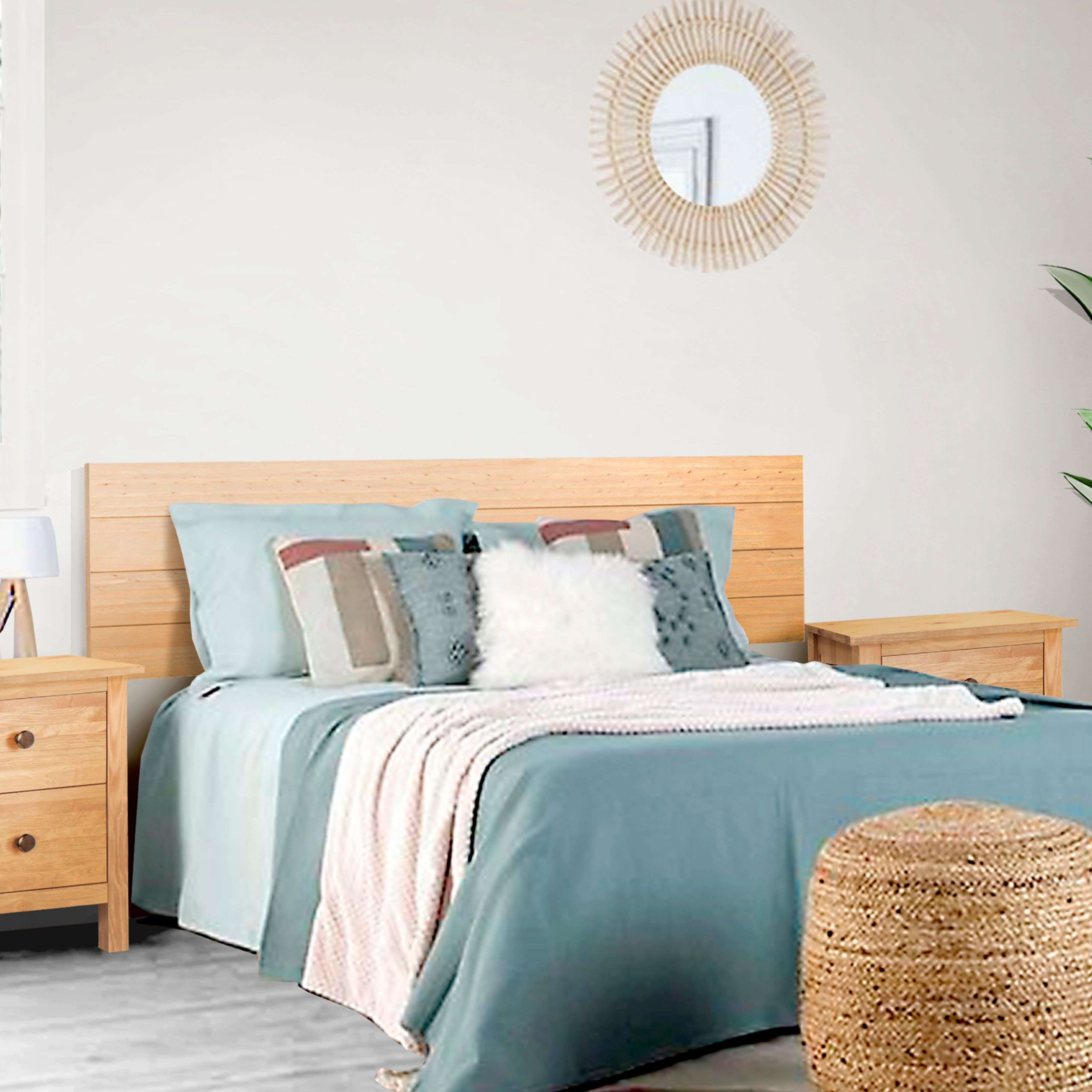 Una cama de madera con ropa de cama azul, almohadas, una manta y mesitas de noche.