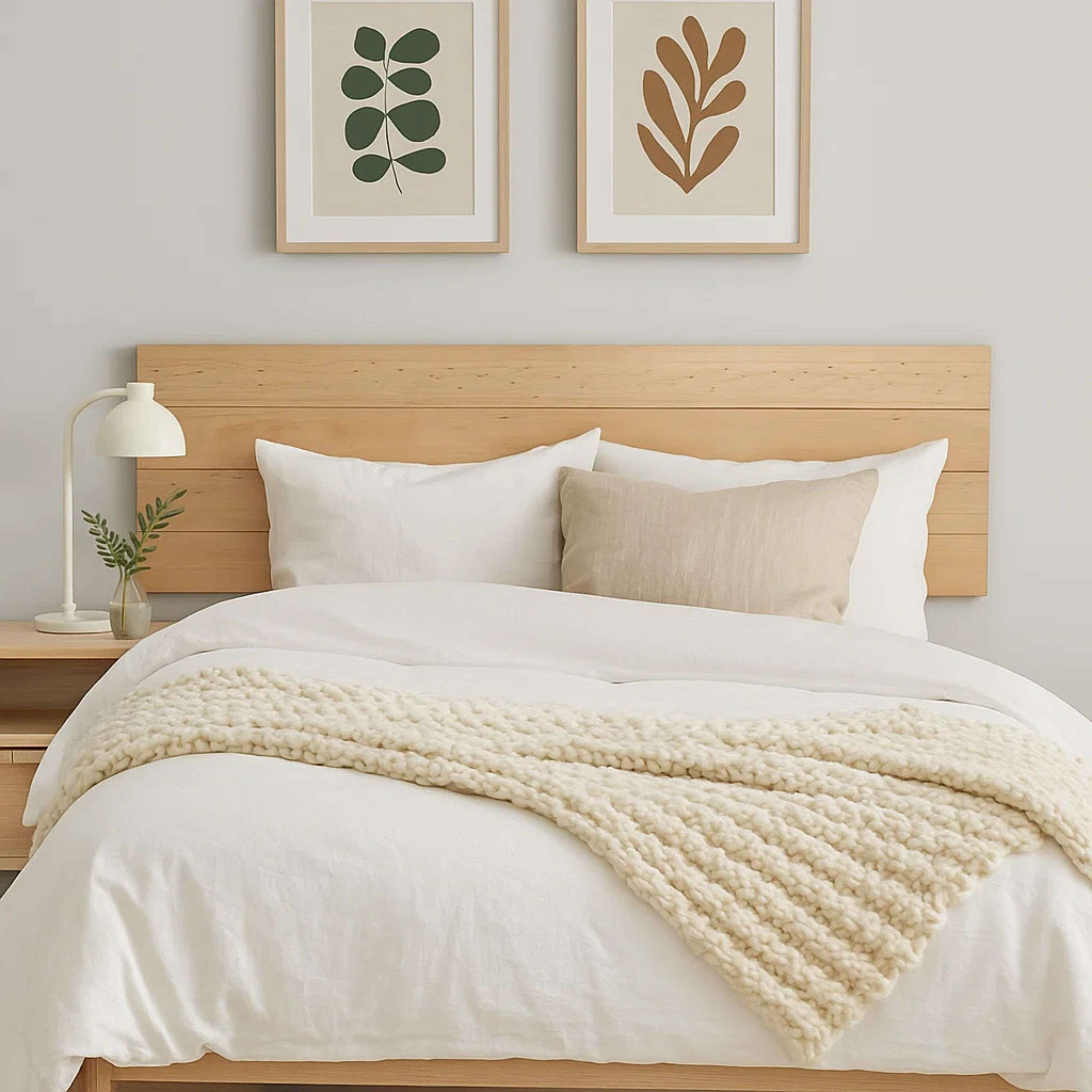 Una cama con sábanas blancas, un cabecero de madera y dos cuadros.