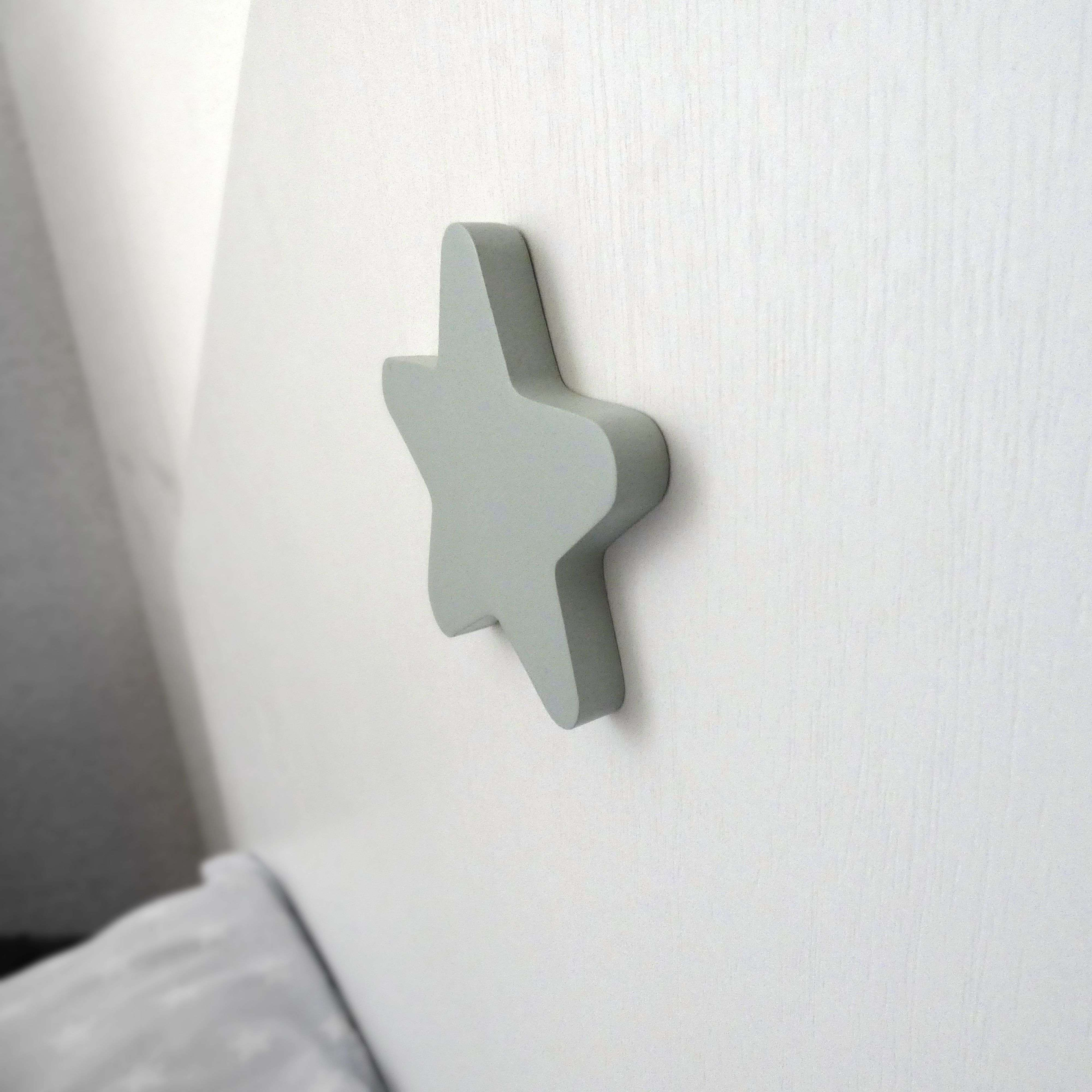 Una estrella gris de madera cuelga de una pared blanca.