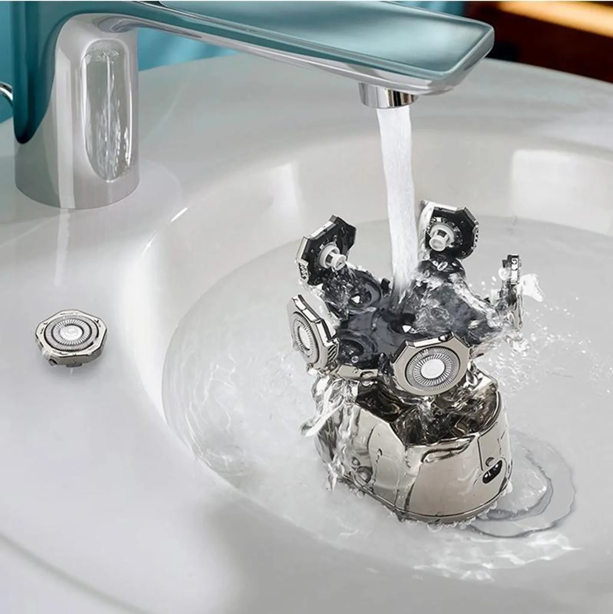 Ein Rasierkopf wird unter fließendem Wasser in einem weißen Waschbecken gereinigt.