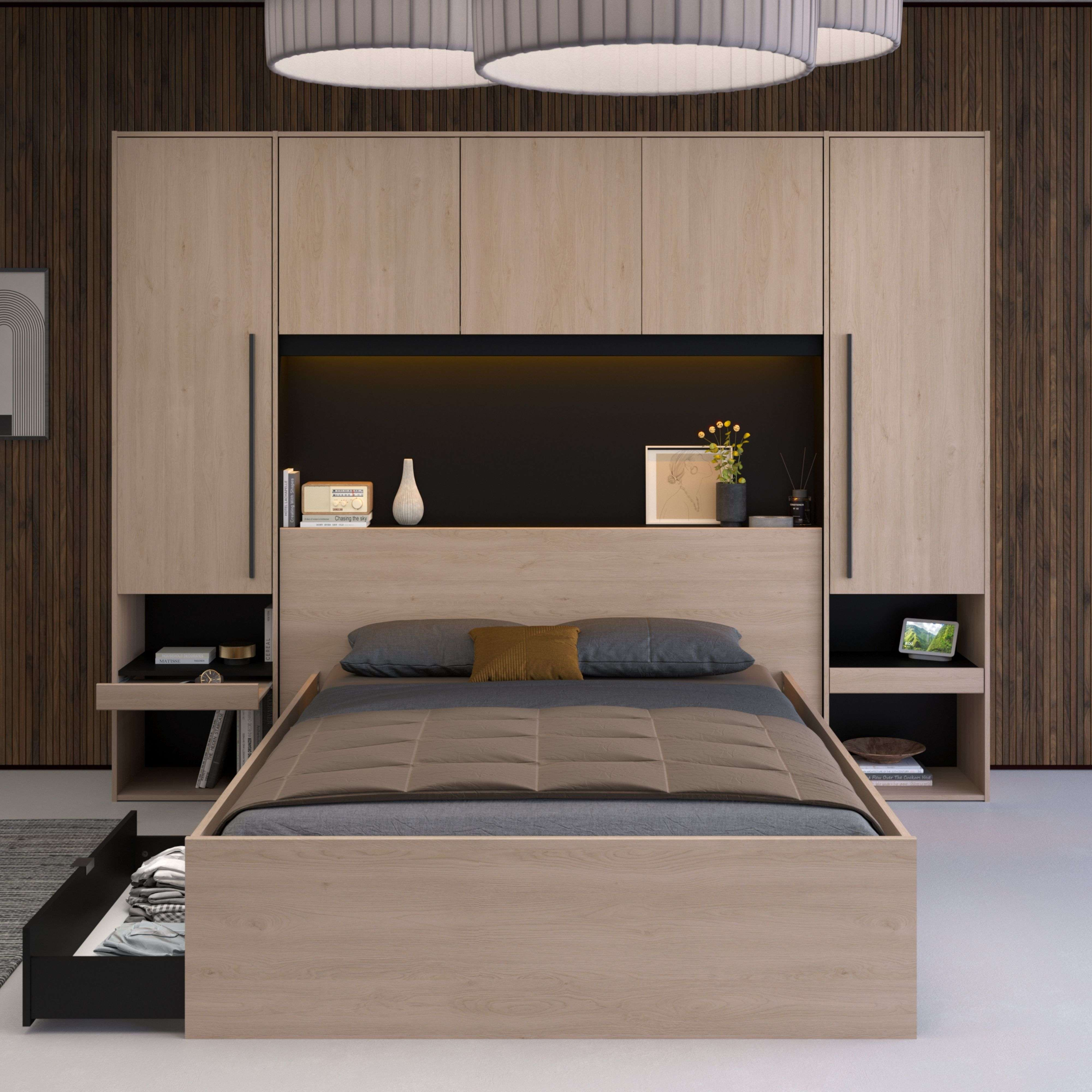 Cama de madera con mesitas de noche, cajones y armarios empotrados. Decorada con libros y jarrón.