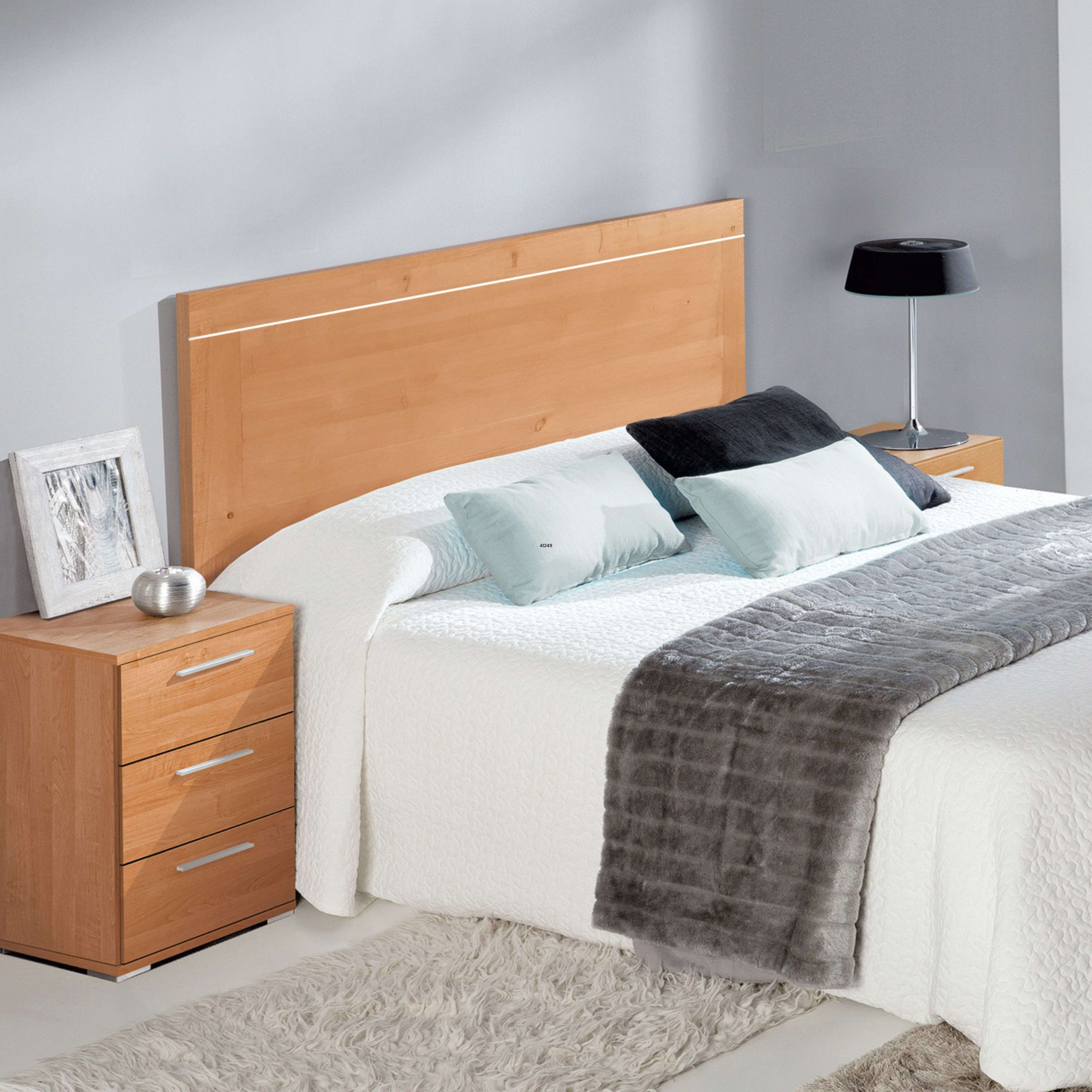 Cama de madera con mesitas de noche, cojines, manta y lámpara.