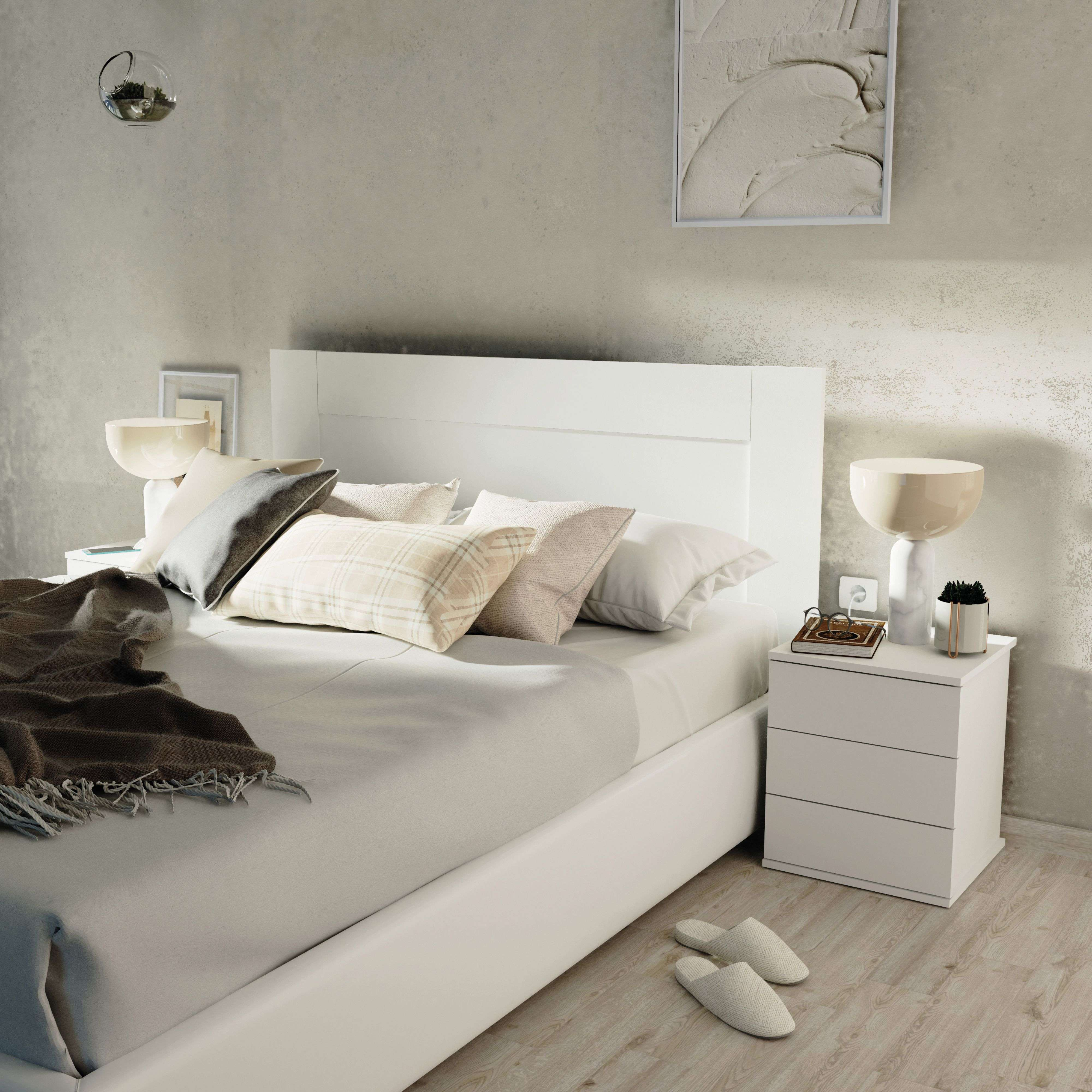 Un dormitorio moderno con cama blanca, almohadas, manta y mesitas de noche.