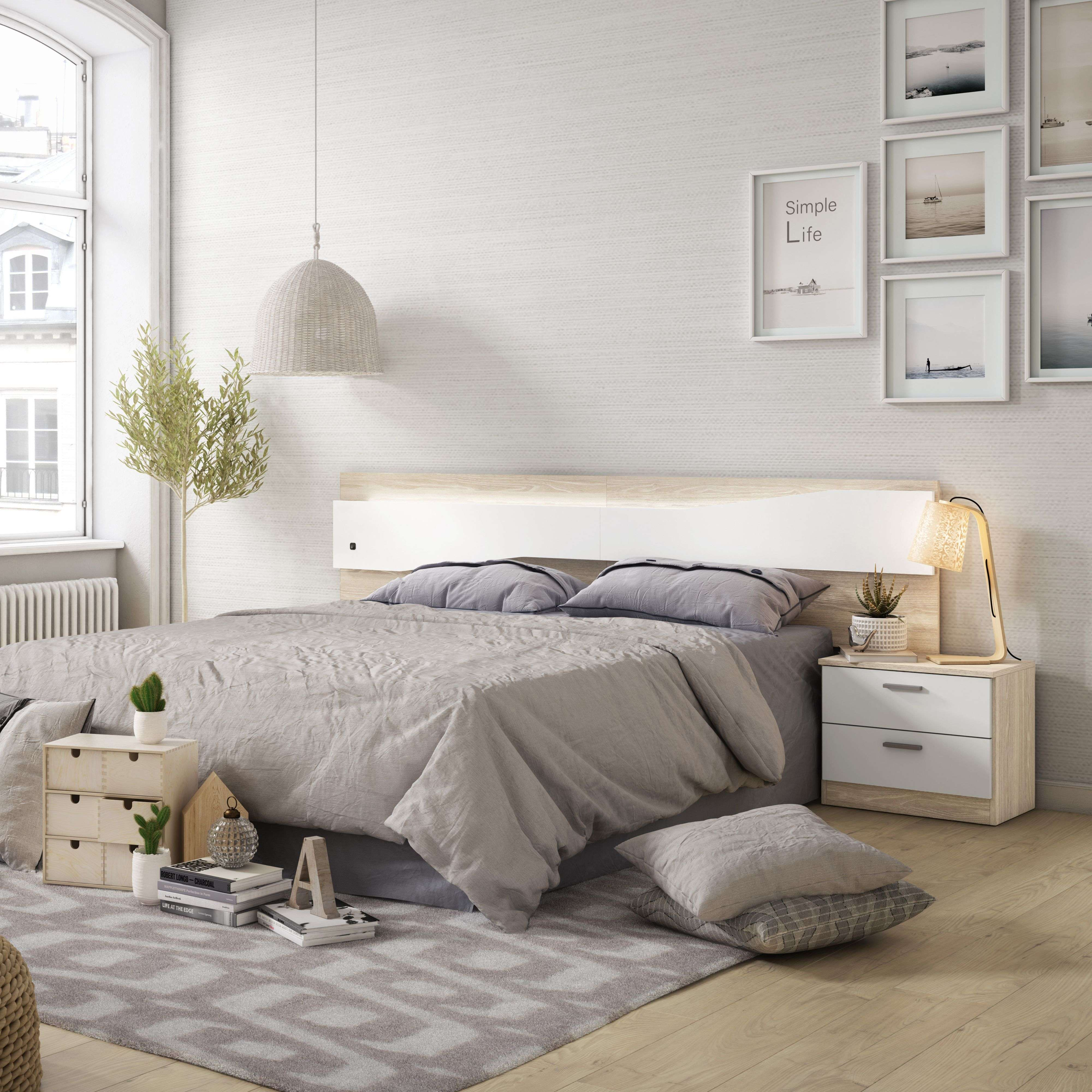 Dormitorio moderno con cama grande, mesitas de noche y cuadros en la pared.