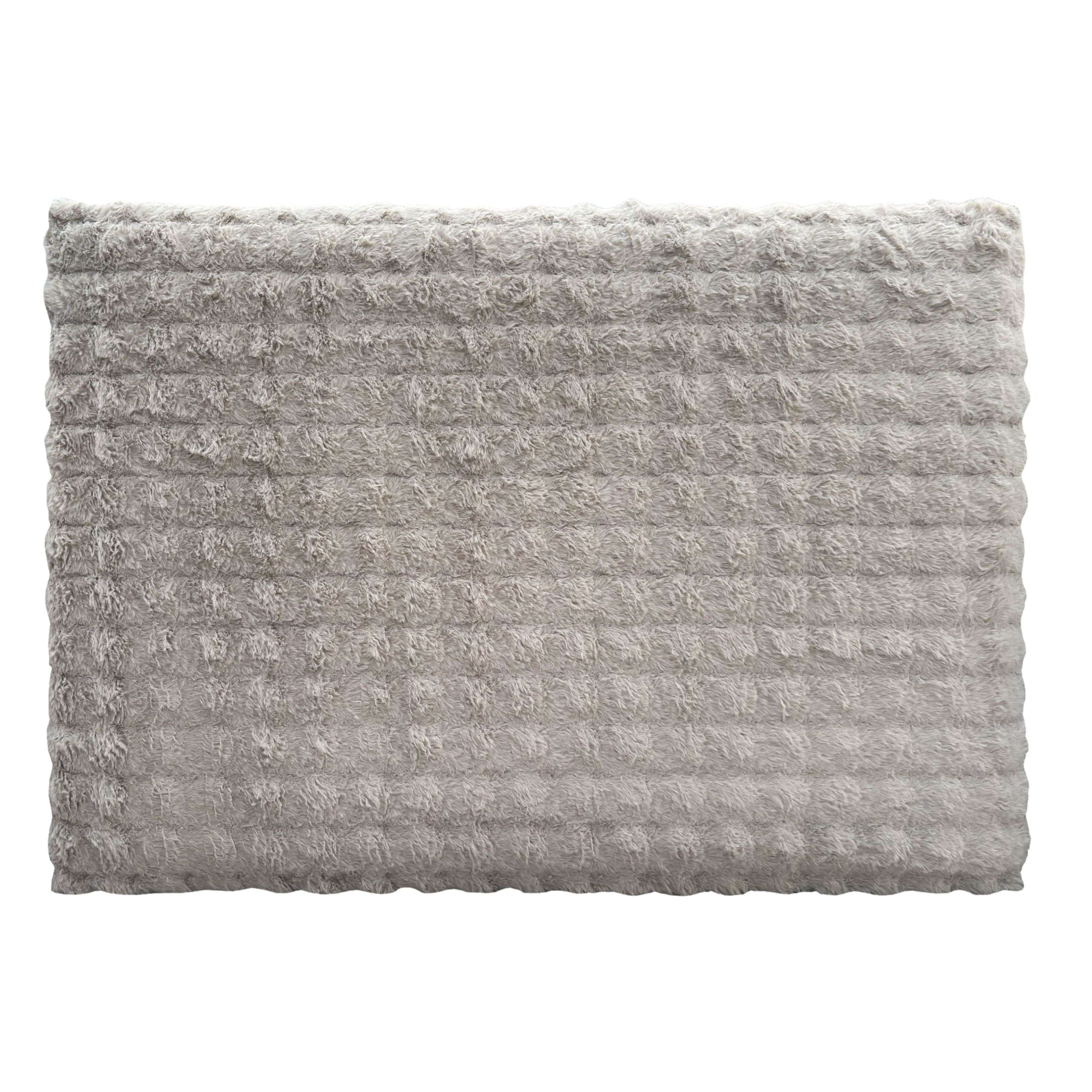 Alfombra gris y esponjosa con textura acanalada y borde ondulado.