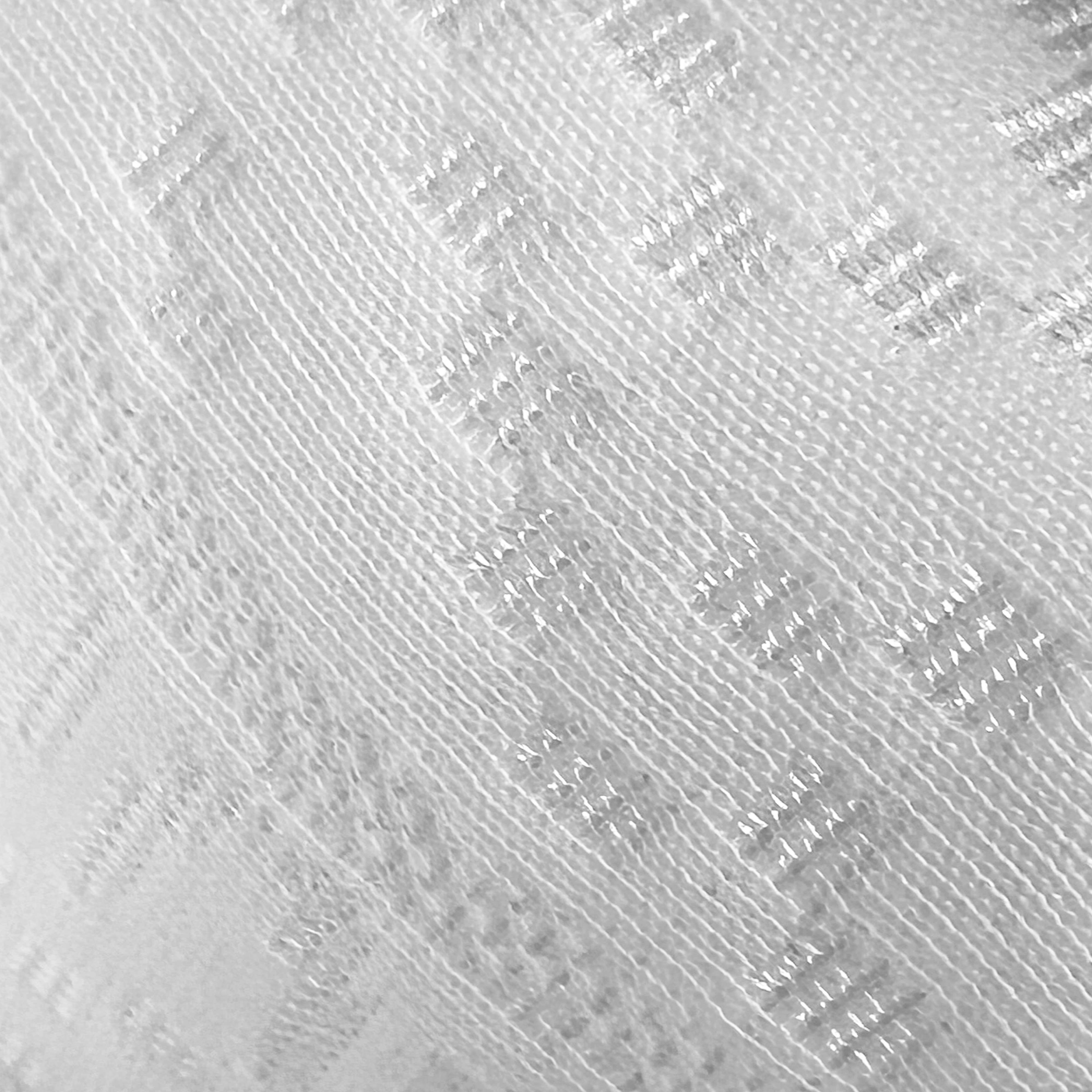 Primer plano de tela blanca con patrones diagonales e hilos brillantes.