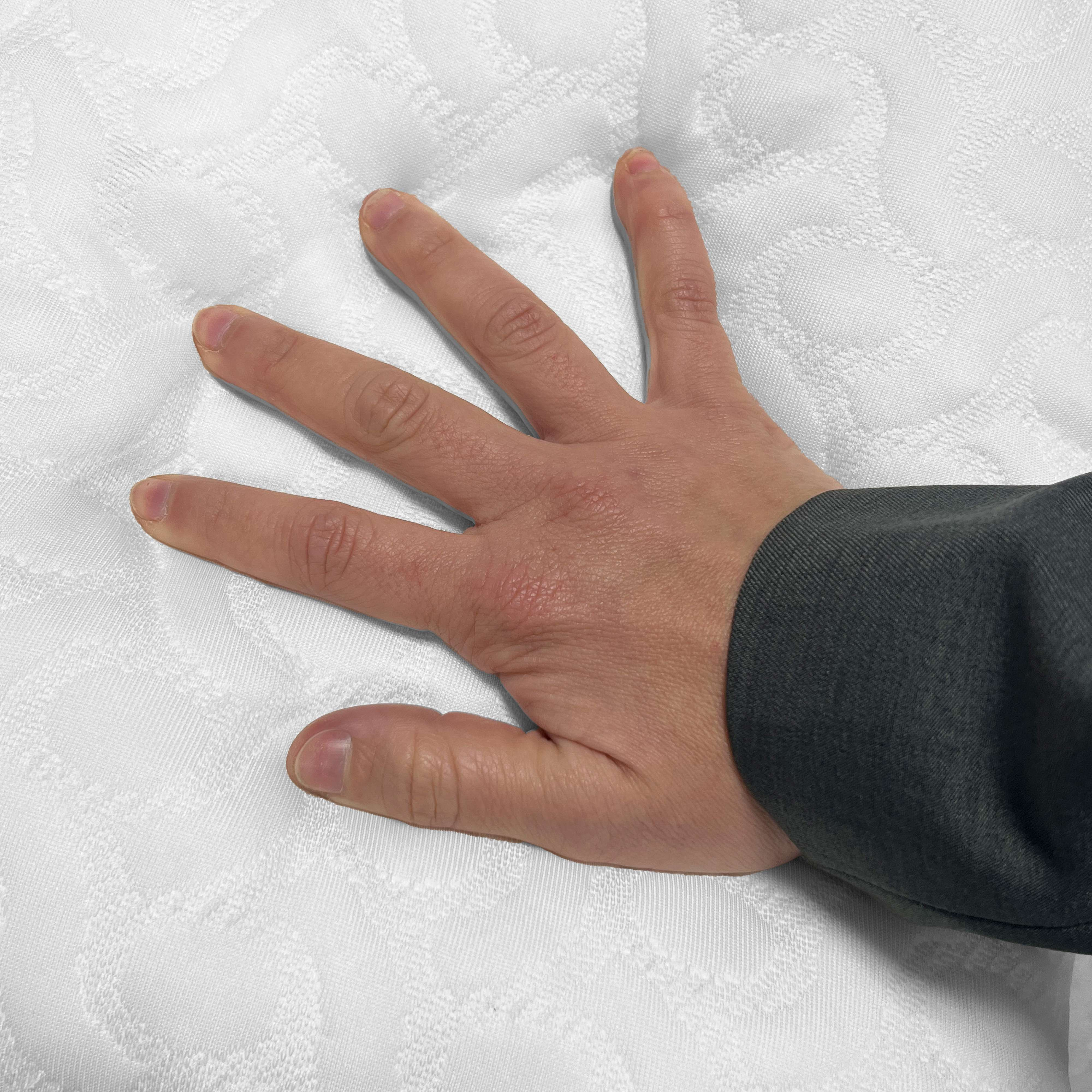 Una mano con los dedos extendidos presiona una superficie blanca acolchada.