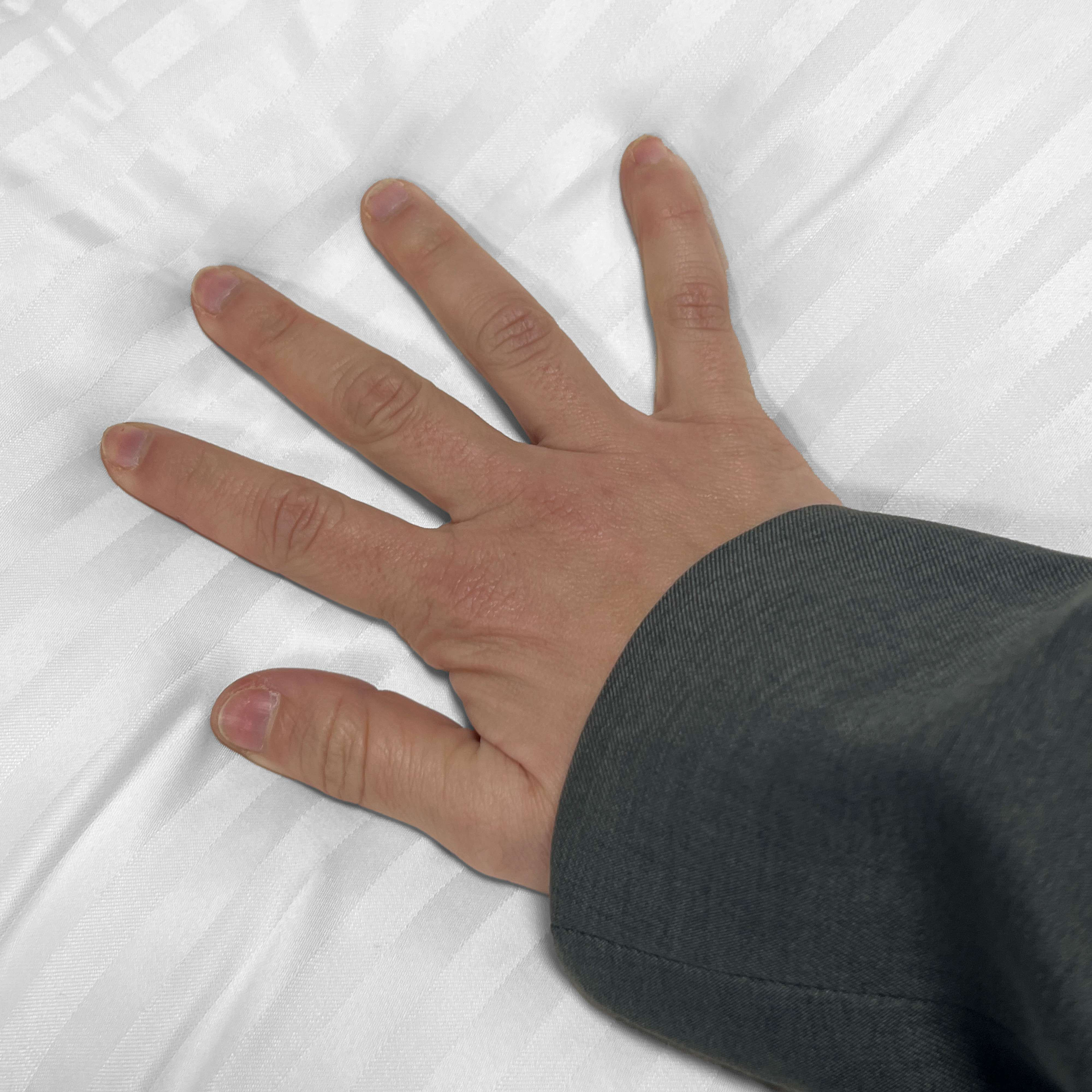Una mano con los dedos extendidos descansa sobre ropa de cama blanca a rayas.