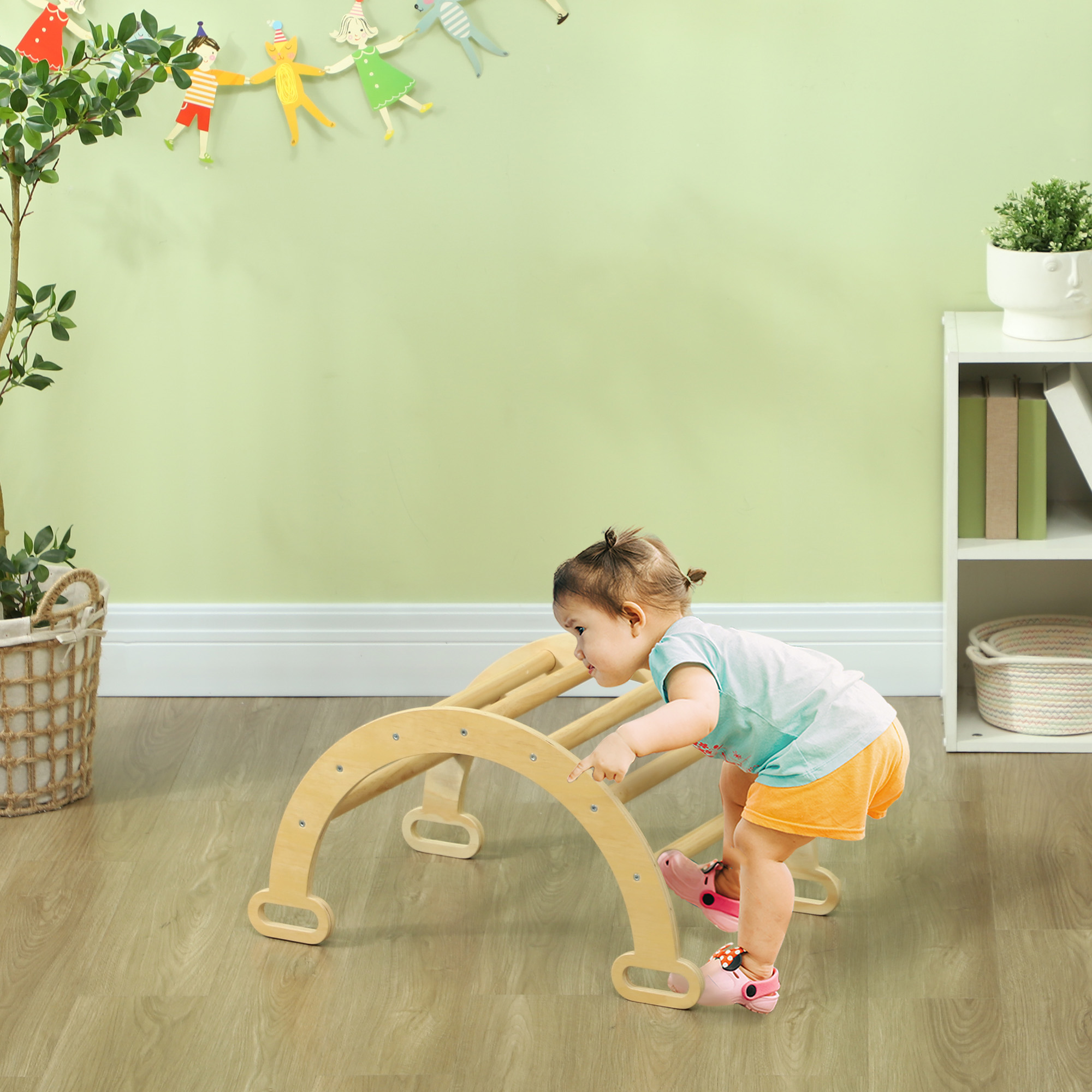 Un niño pequeño trepa en un juguete de arco de madera, con una cesta a la izquierda.