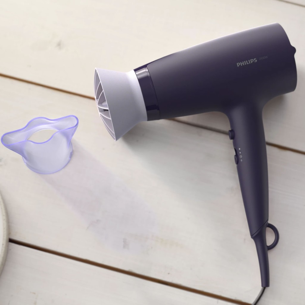 Ahşap zeminde beyaz nozullu ve mor ataçmanlı koyu mor Philips saç kurutma makinesi.