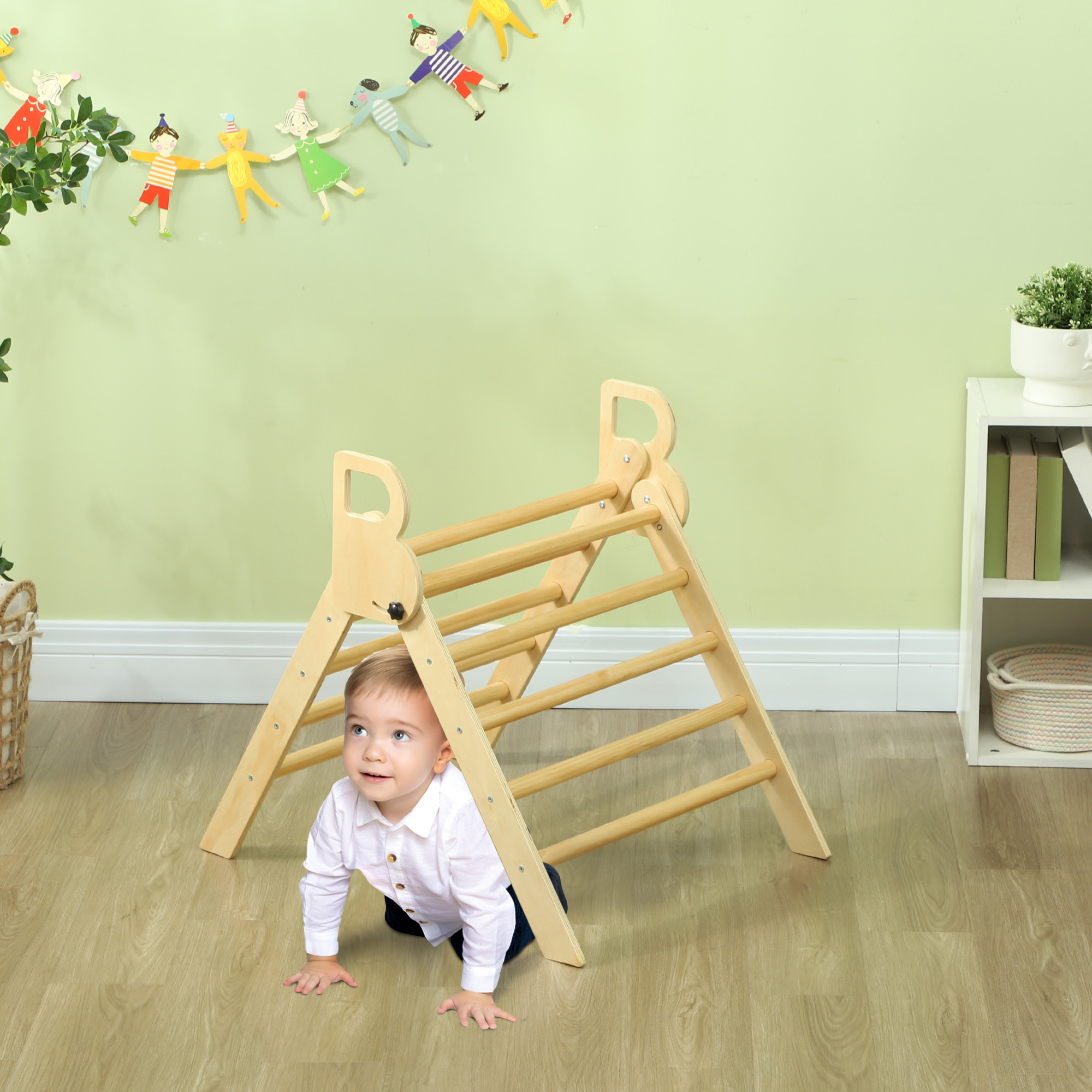 Un bebé gatea bajo una estructura de escalada de madera. Hay decoraciones colgadas en la pared.
