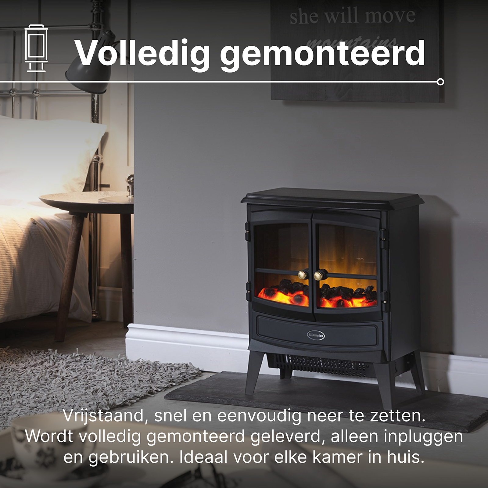 A freestanding black electric fireplace with flame effect stands beside a bed.