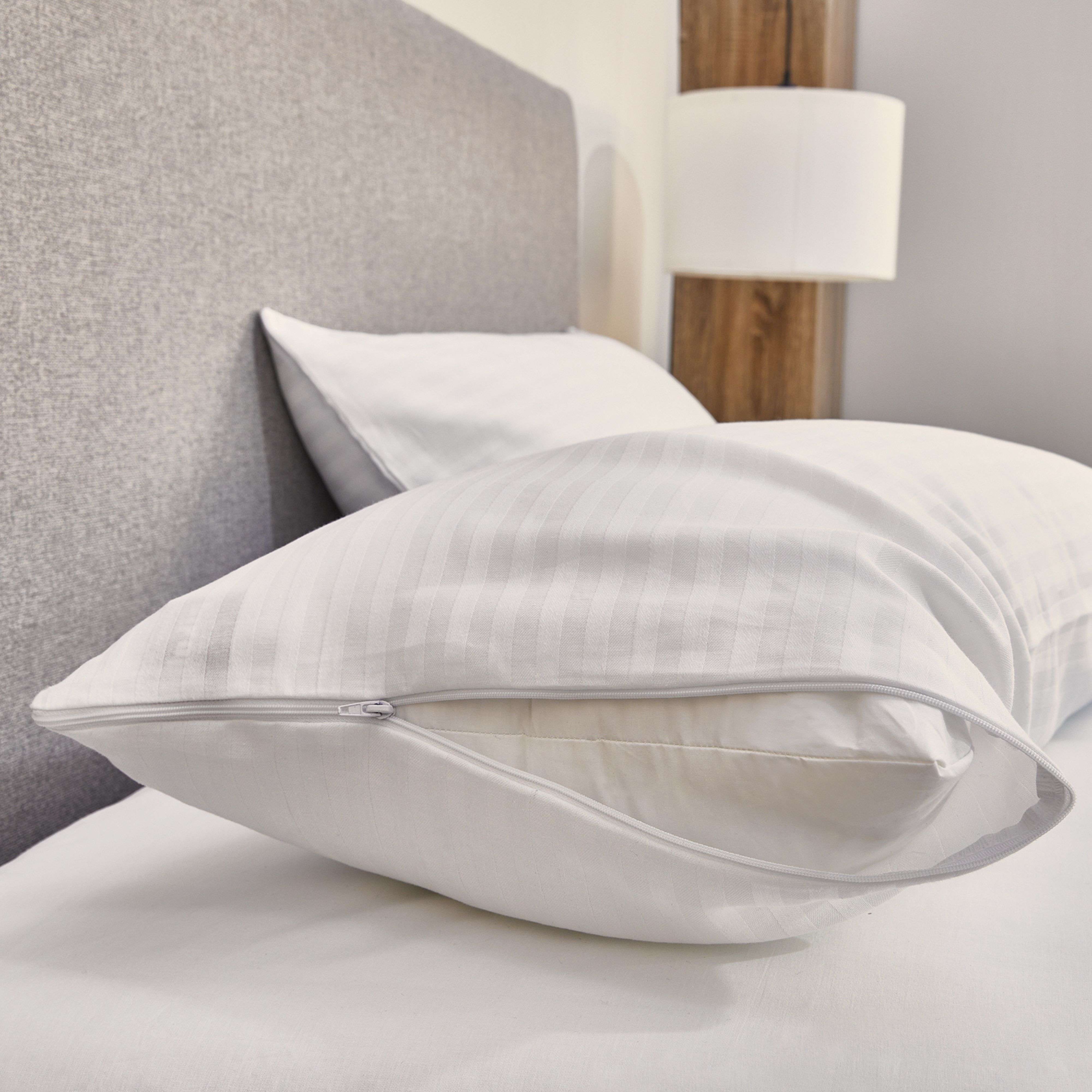 Una almohada blanca a rayas con cremallera abierta en una cama.