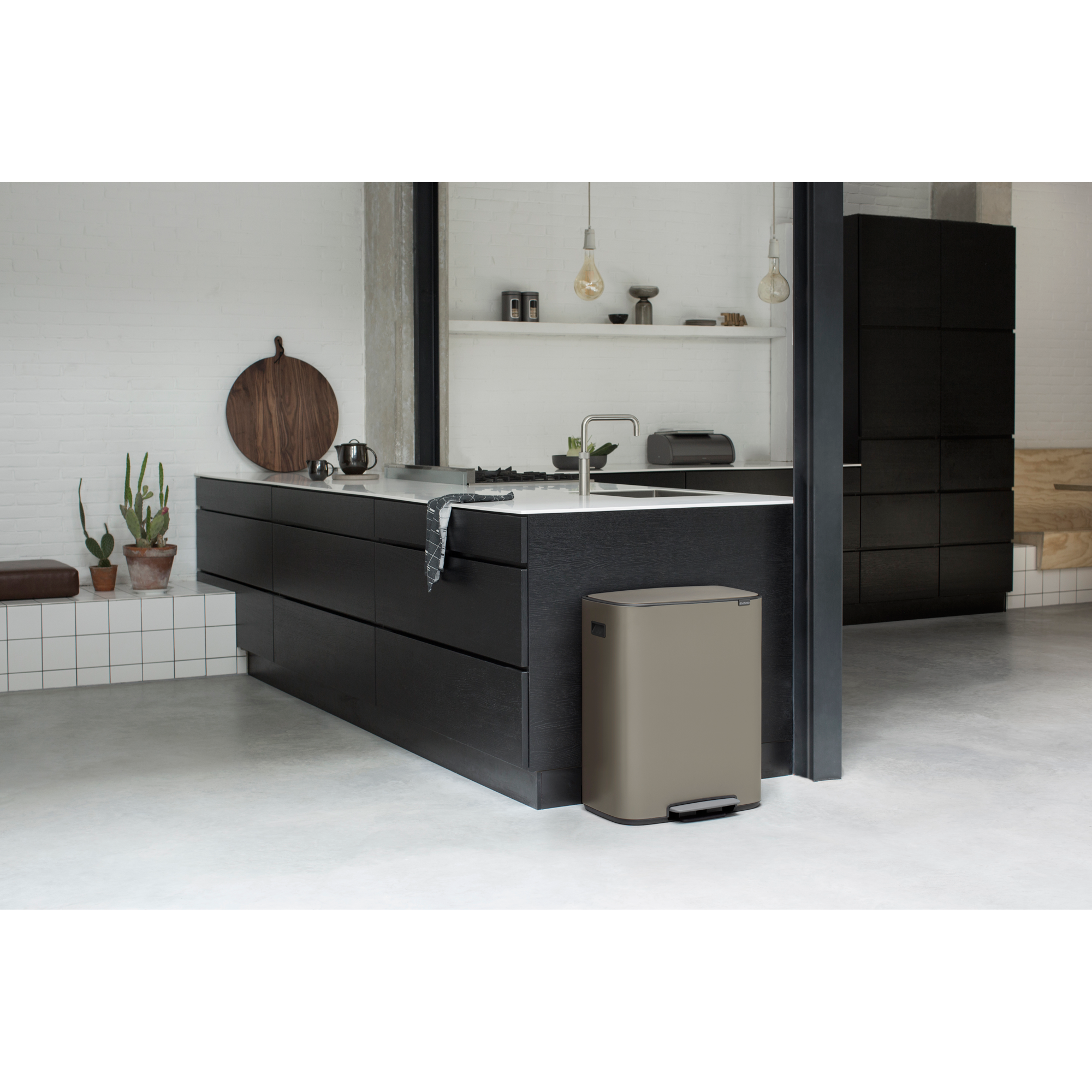 Modern kitchen with dark cabinets, stone island, and trash bin.