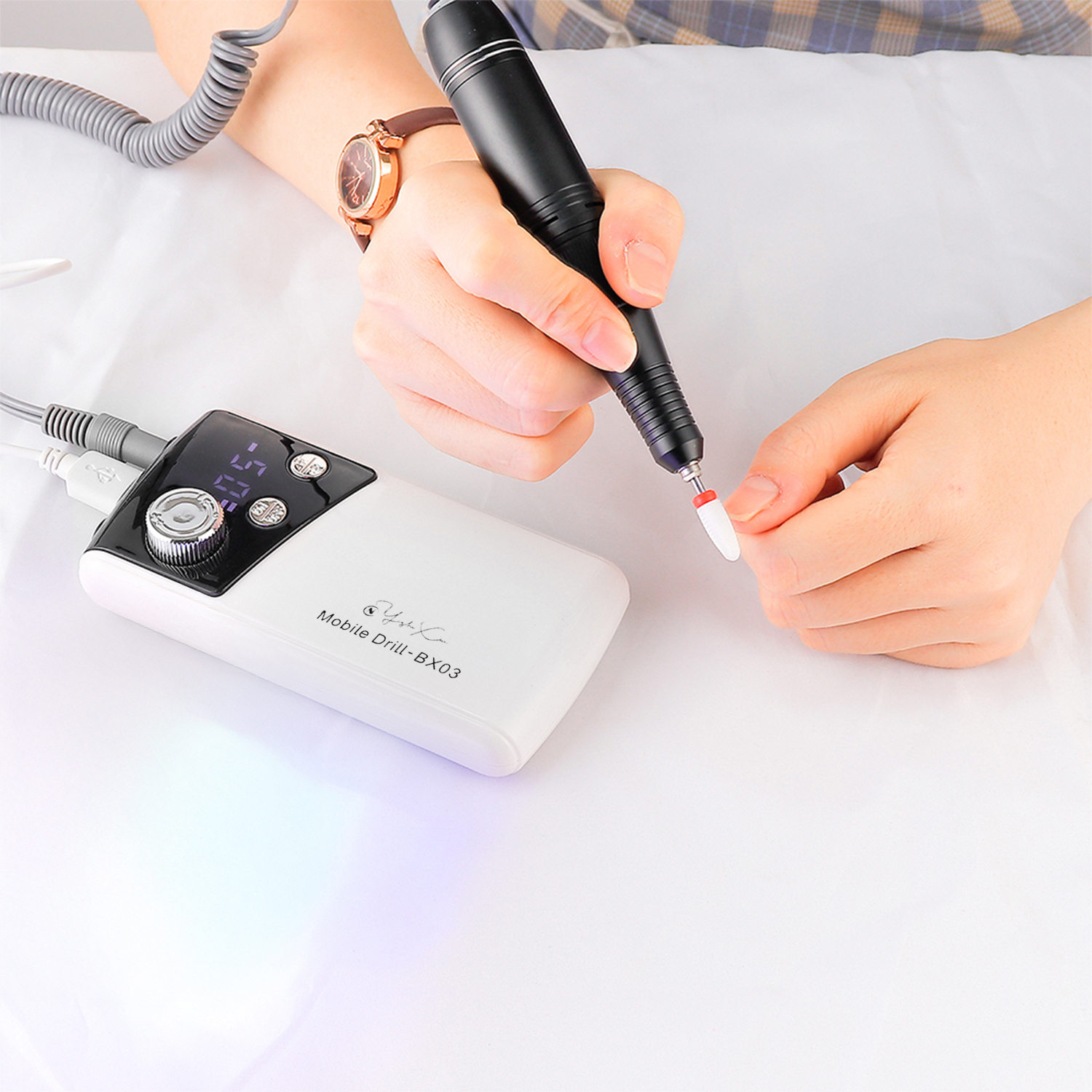 Una mano usa un trapano elettrico per unghie per fare una manicure.