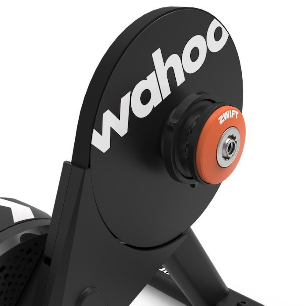 Czarny trenażer rowerowy z pomarańczowym kołem Zwift i logo Wahoo.