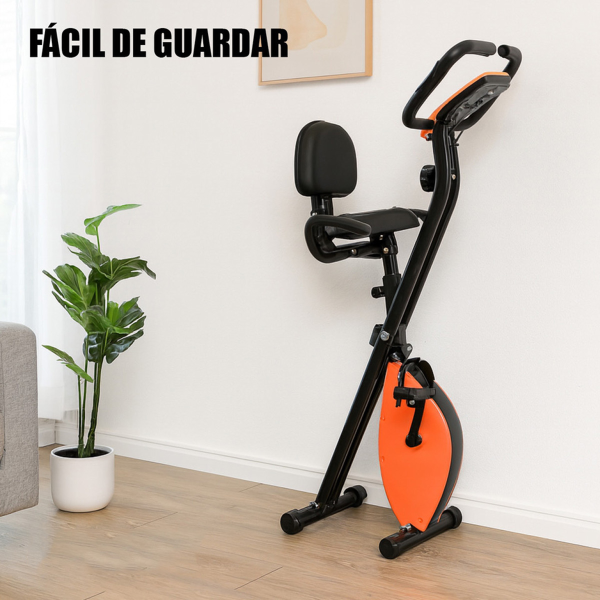 Una bicicleta estática negra con detalles naranjas sobre suelo de madera junto a una planta.