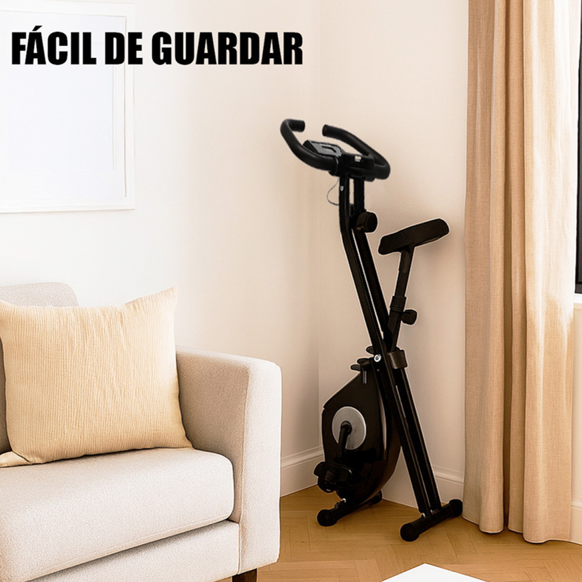 Bicicleta estática plegable negra junto a un sofá con cojín. Texto: FÁCIL DE GUARDAR.