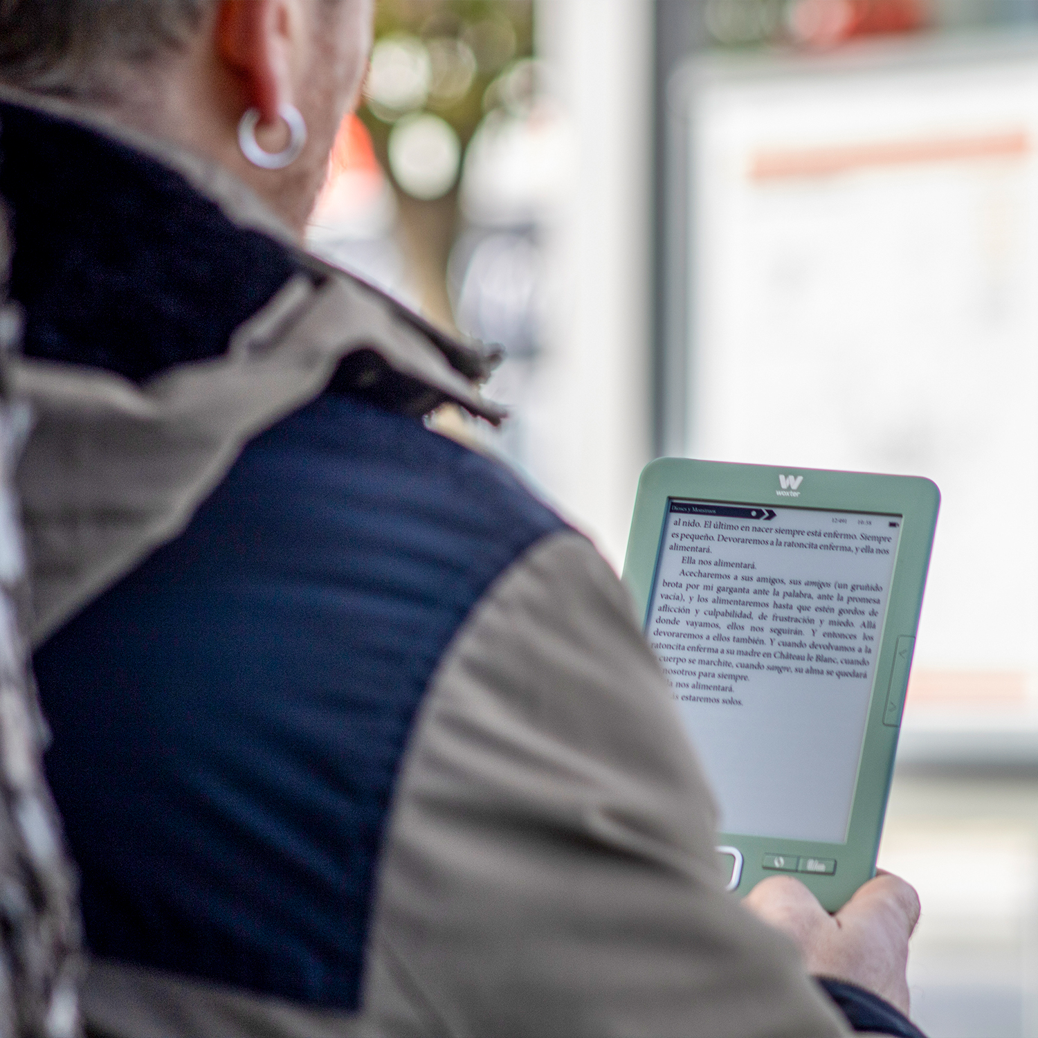 Una persona lee un libro electrónico en un dispositivo verde que sostiene.