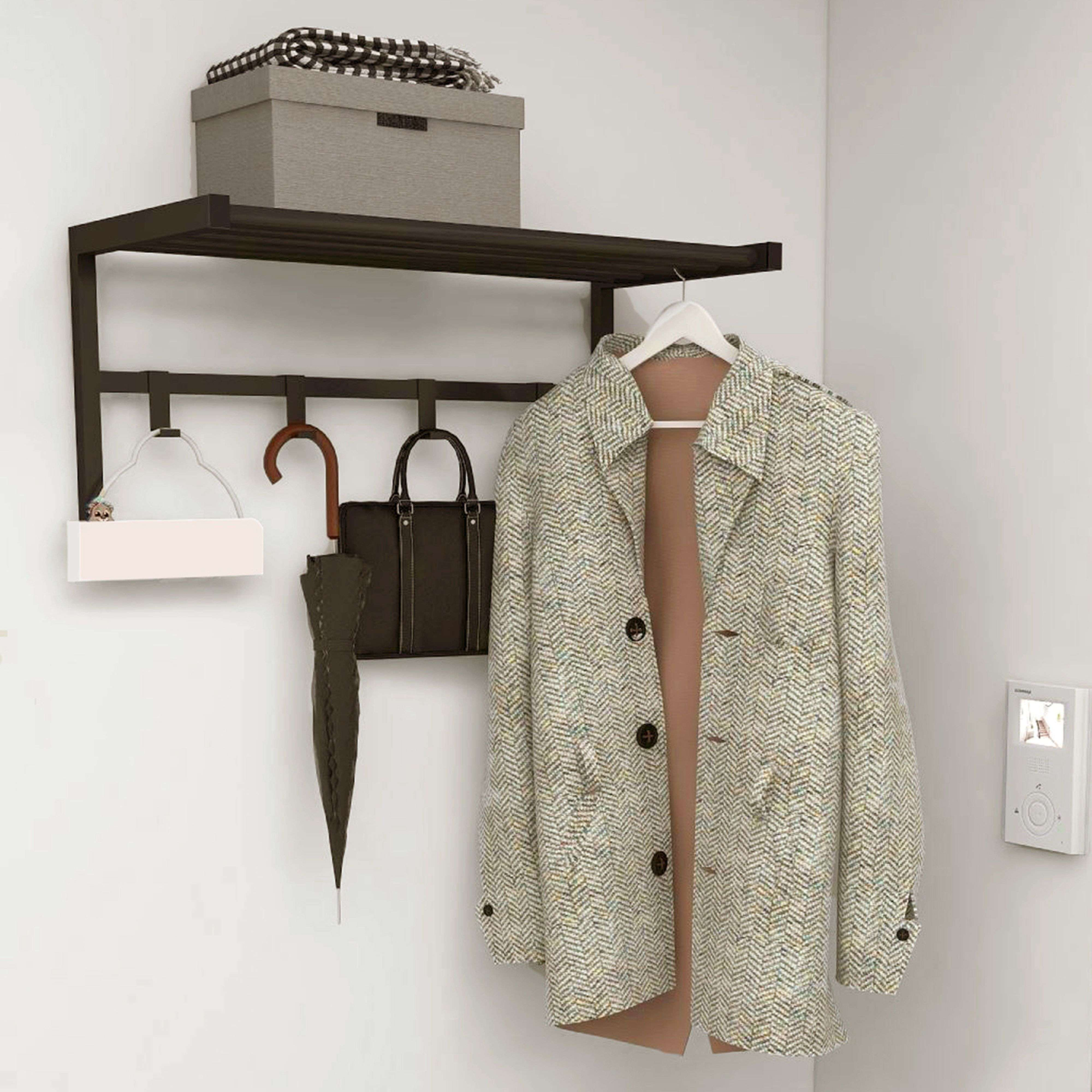 Un abrigo cuelga en un estante de pared con bolsos y paraguas.