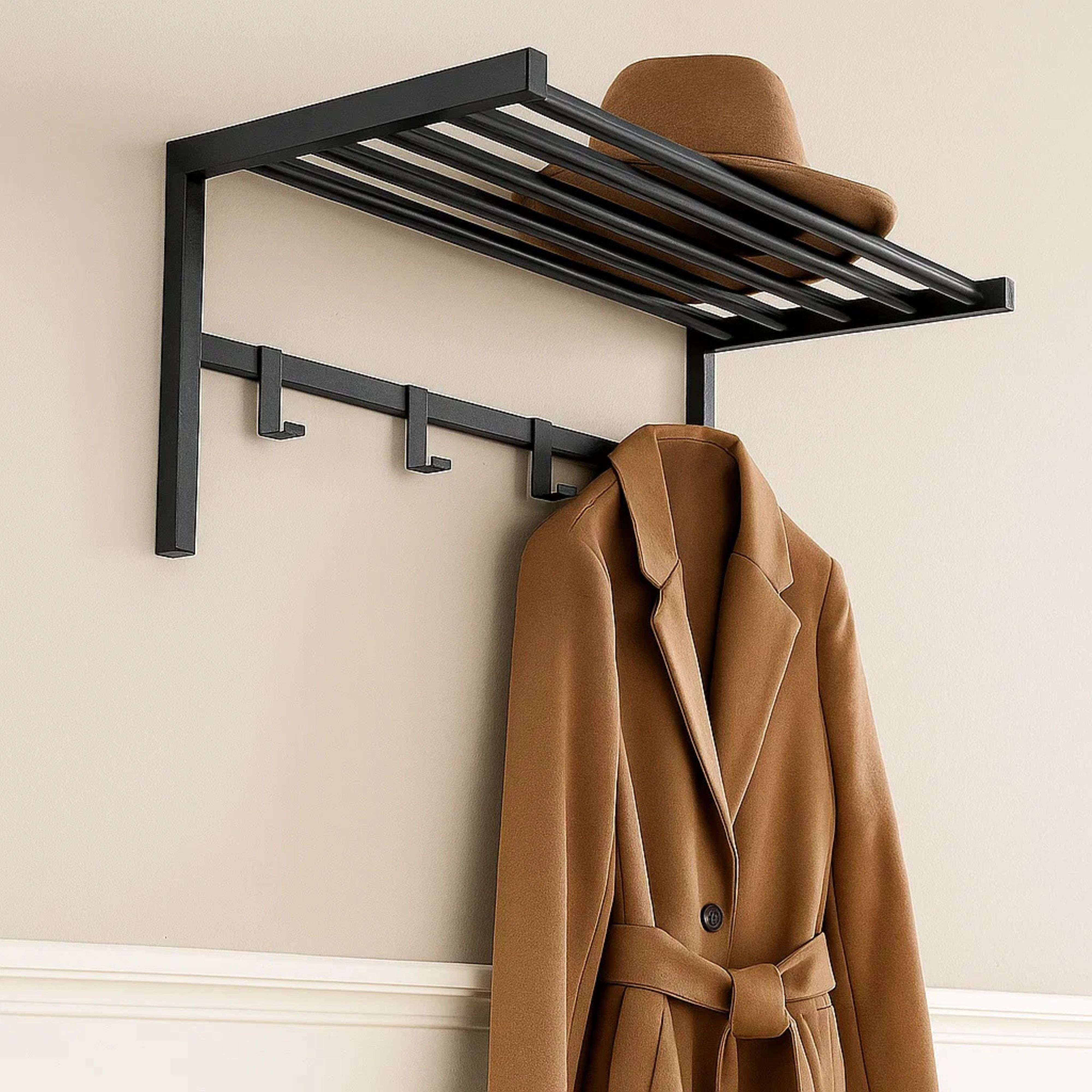 Perchero de pared negro con ganchos, un sombrero marrón y un abrigo.