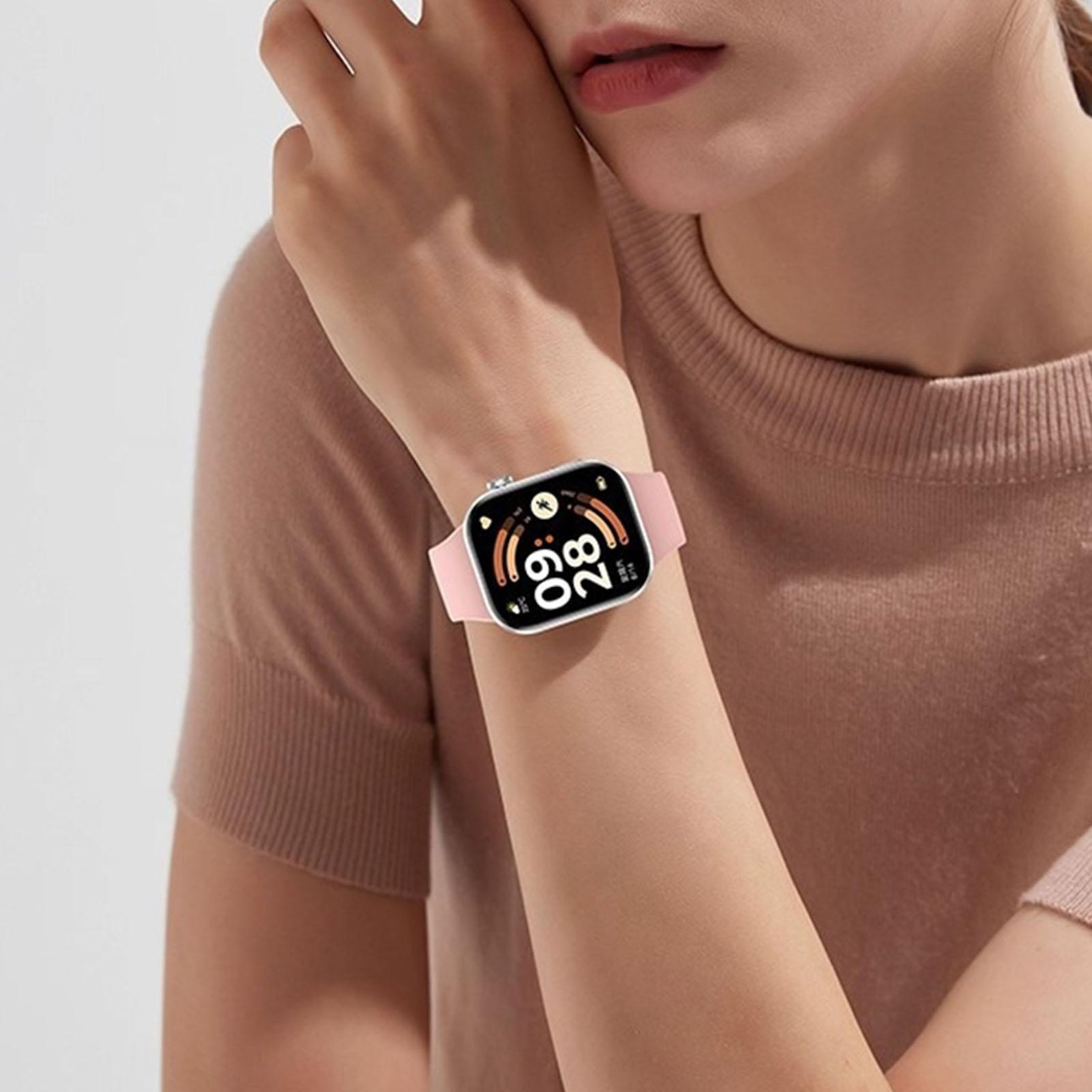 Eine Person trägt eine Smartwatch mit pinkfarbenem Armband am linken Handgelenk.