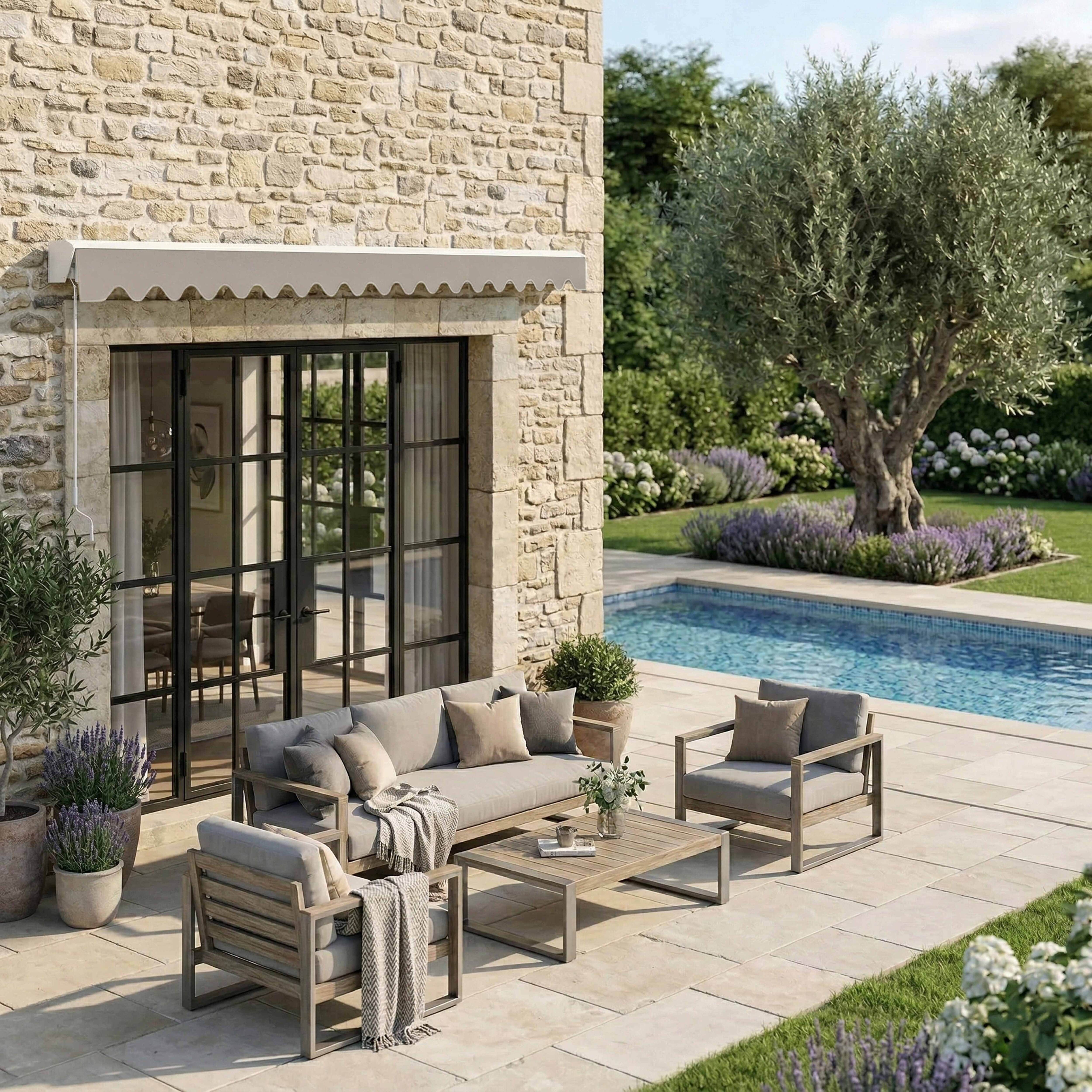 Gartenmöbel neben einem Pool, mit altem Olivenbaum und Steinhaus.