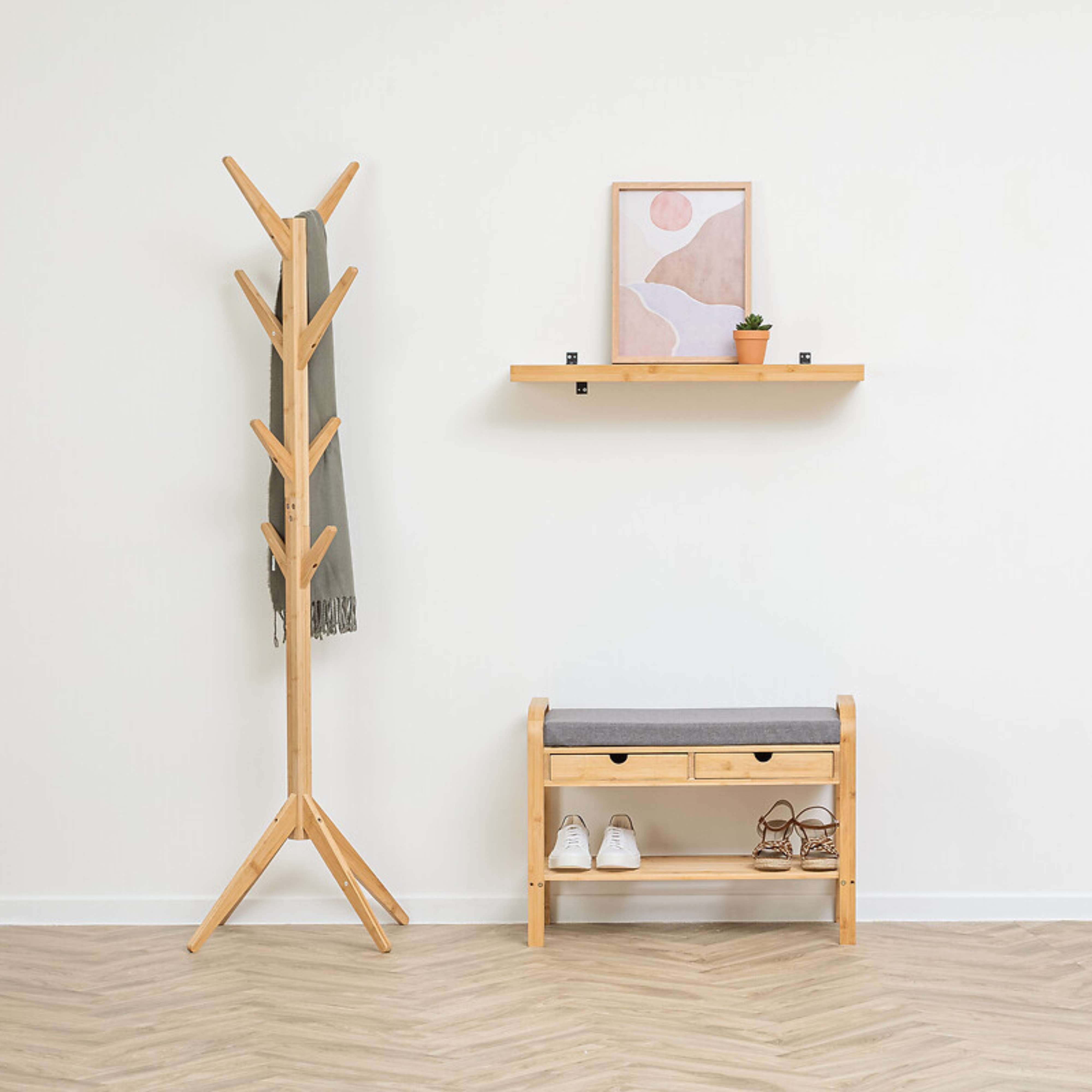 Perchero de madera con bufanda, banco de zapatos con zapatos y estante con arte.