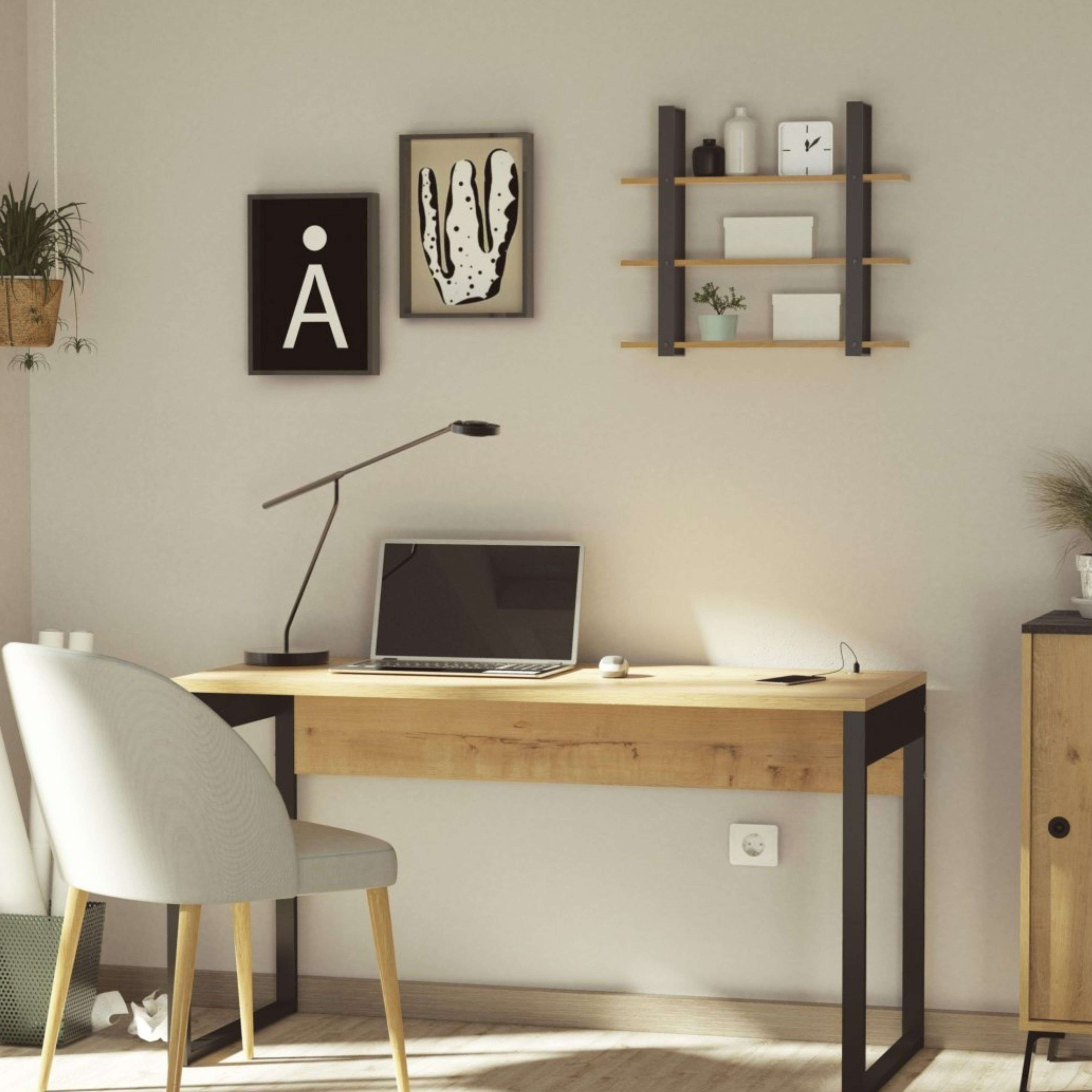 Un escritorio con portátil, lámpara y silla en una habitación luminosa con decoración de pared.