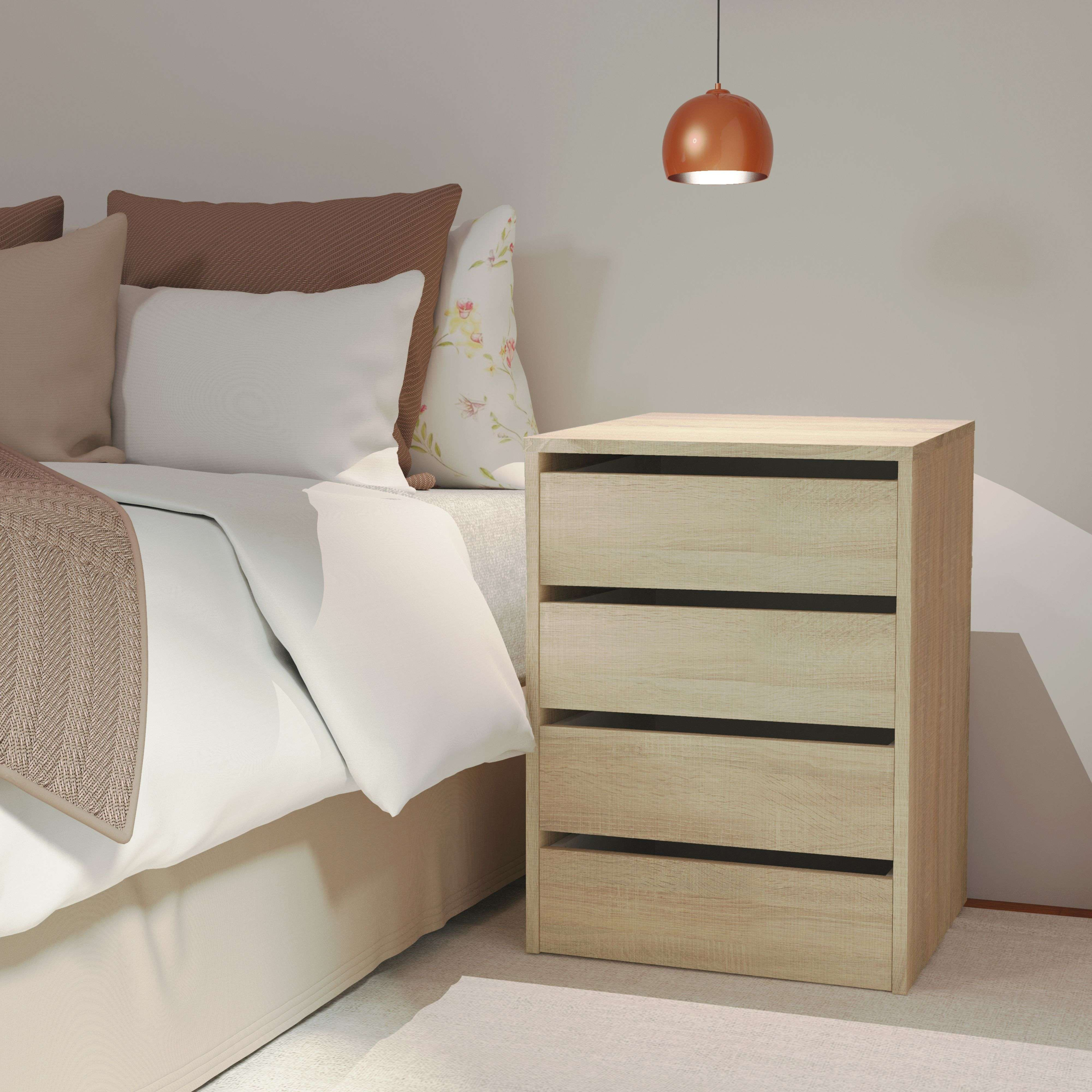 Una mesita de noche de madera clara junto a una cama con almohadas blancas y marrones.