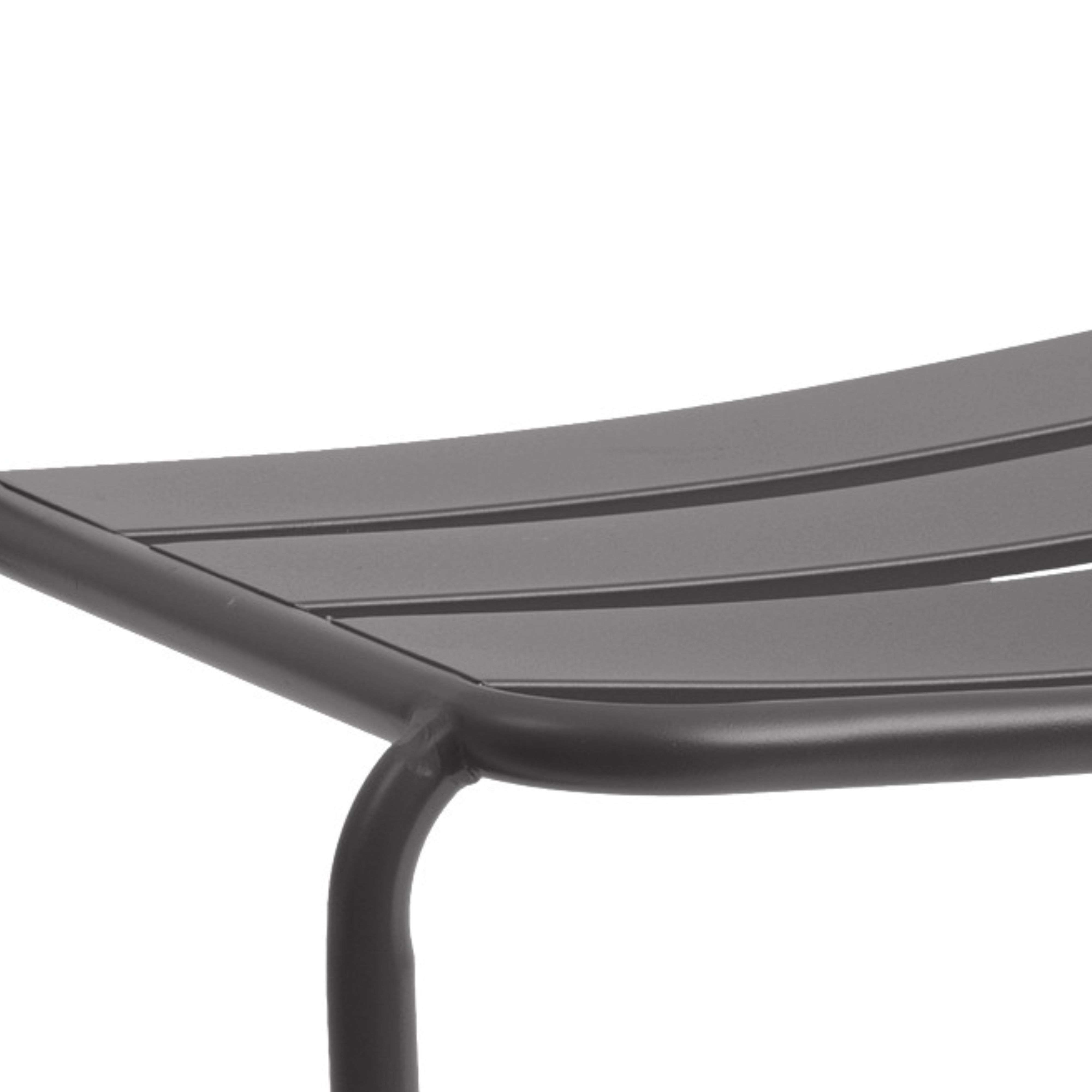 Primer plano de un banco de metal gris oscuro con listones paralelos y soporte curvo.