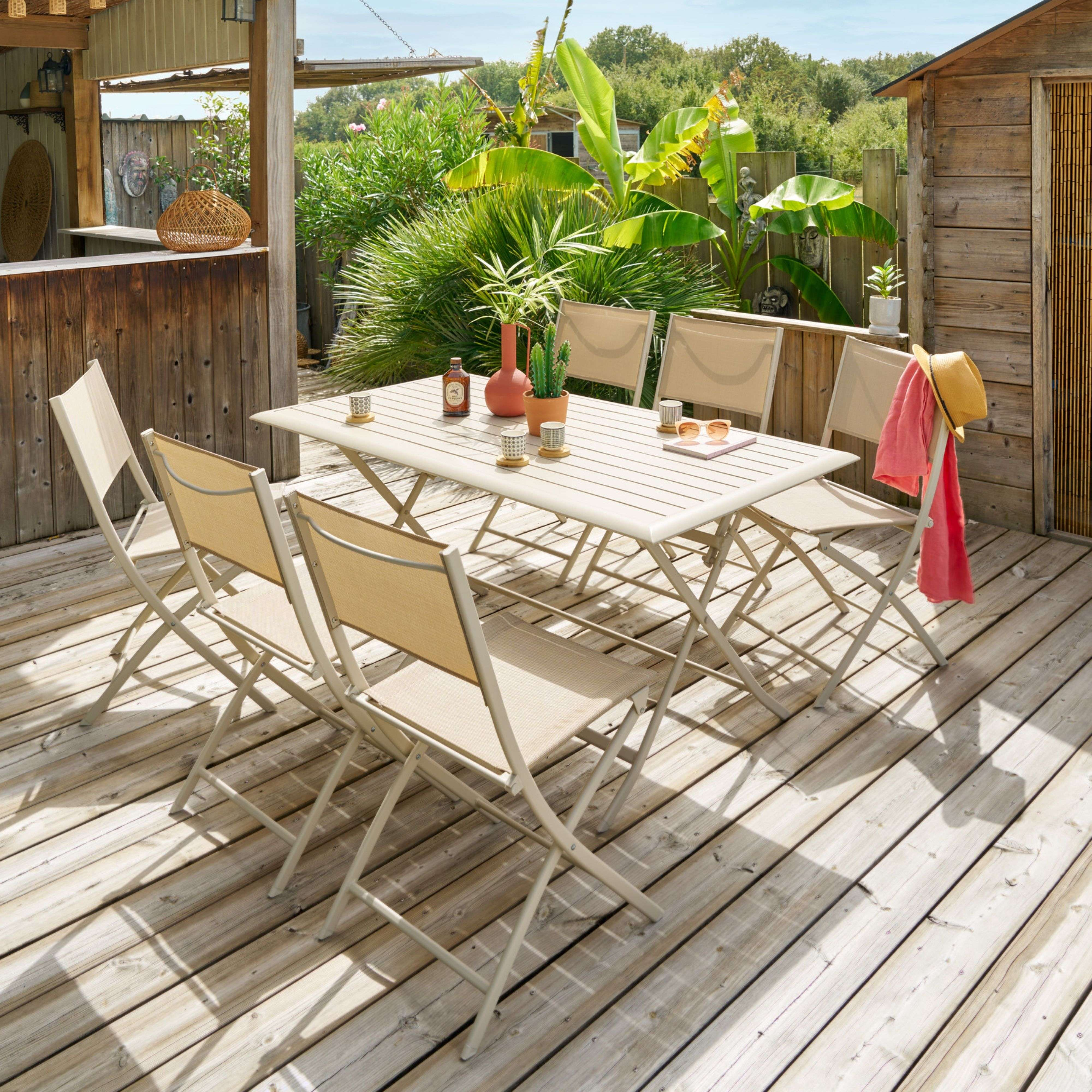 Un patio ajardinado con mesa y sillas, rodeado de vegetación.
