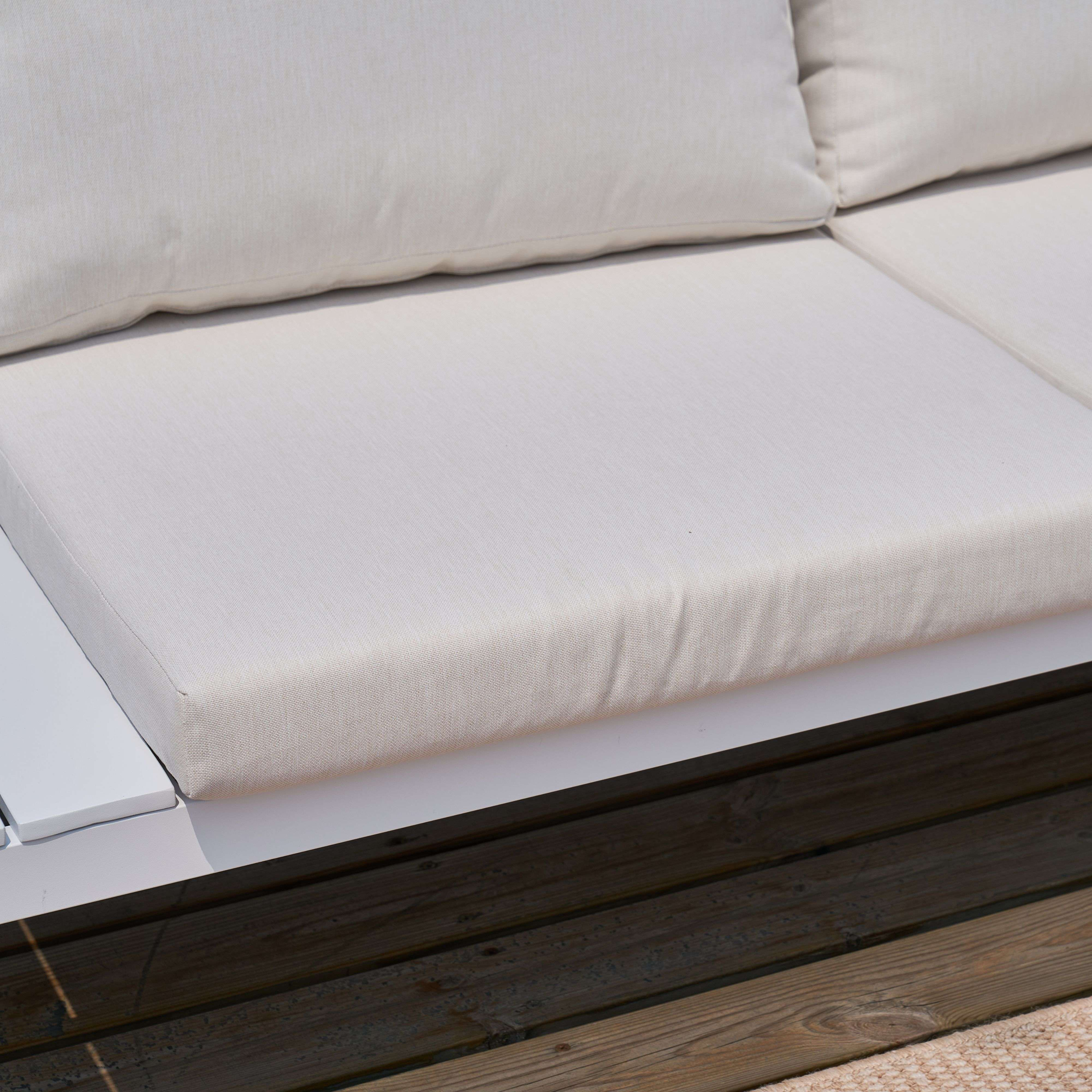 Un cojín de sofá beige descansa sobre una base blanca, junto a tablones de madera.