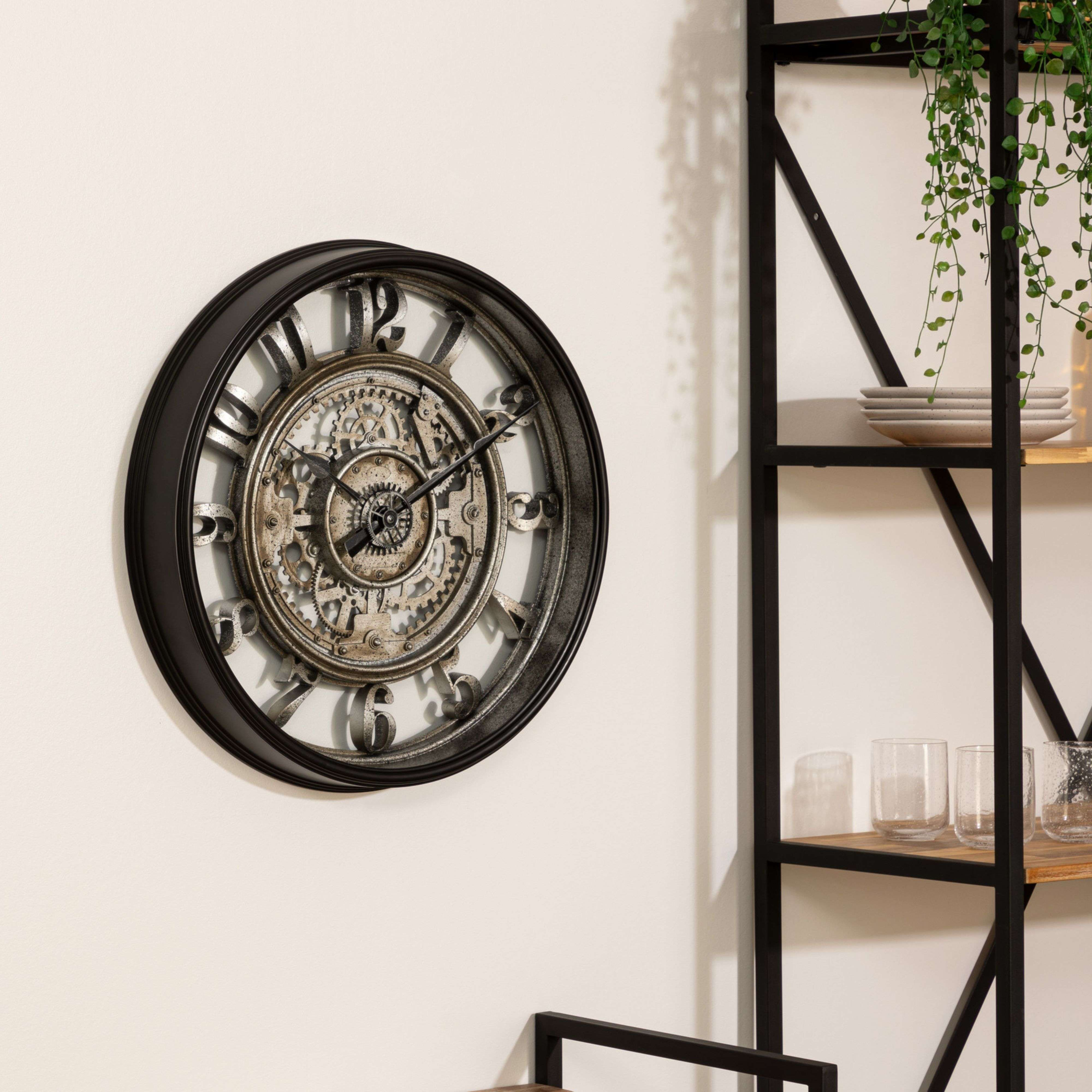 Un gran reloj de pared con marco negro y engranajes mecánicos.