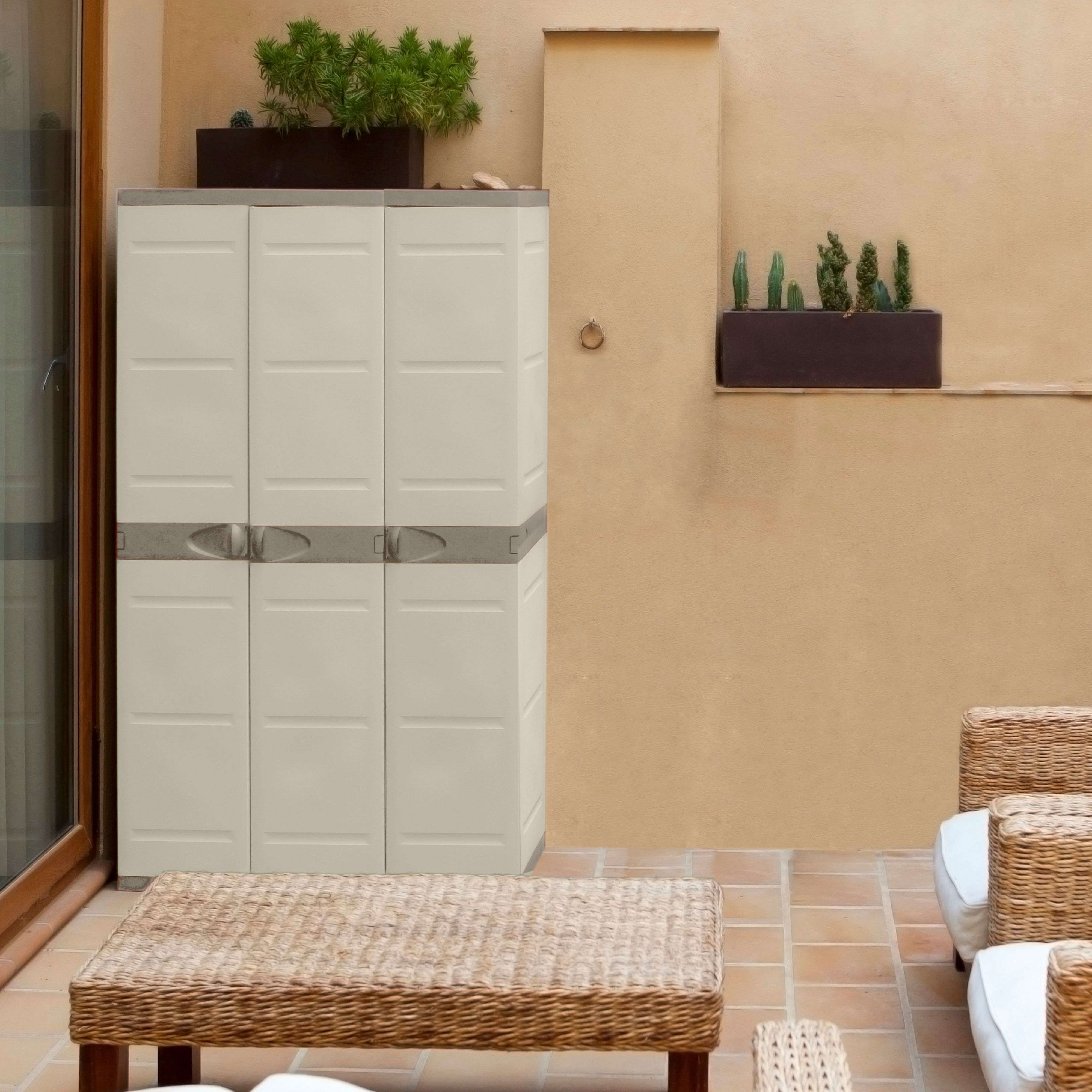 Un armario beige está en un patio embaldosado junto a una mesa y sillas.