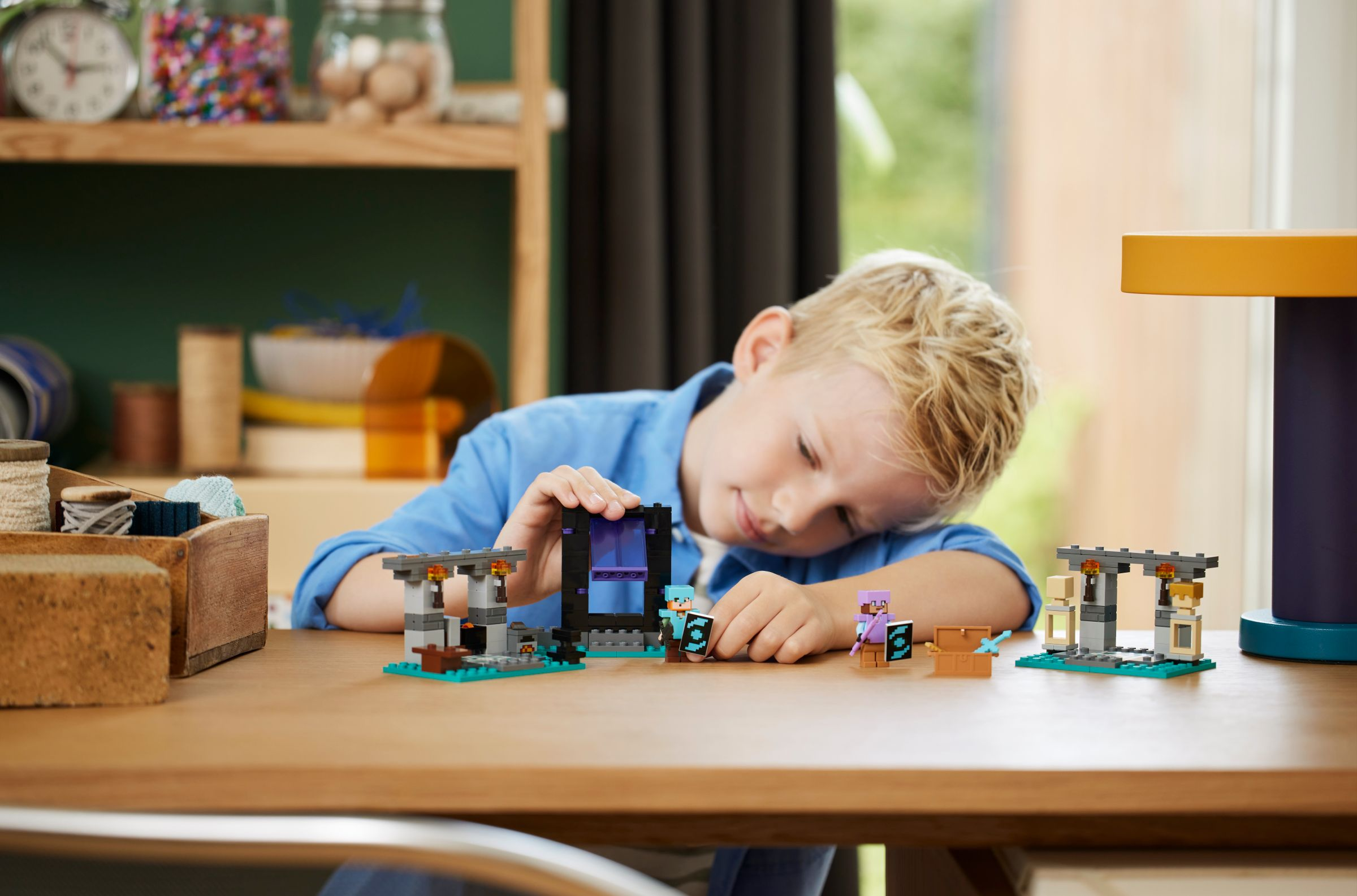 Ein Junge baut mit Minecraft-Legosteinen, mit verschiedenen Figuren und einer Truhe.