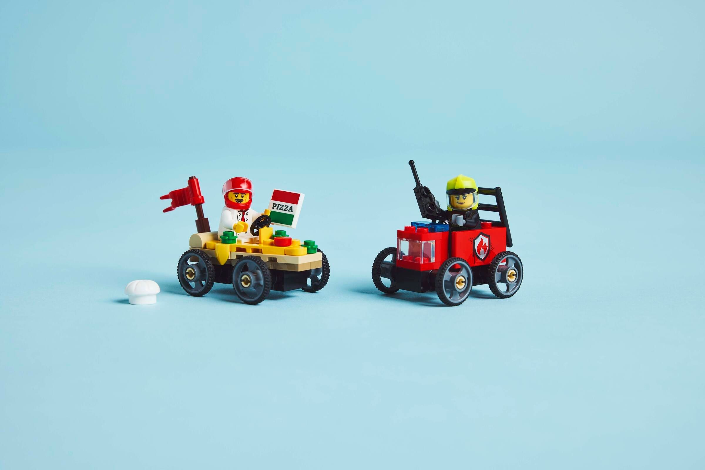 Zwei Lego-Fahrzeuge auf blauem Hintergrund. Eines ist gelb mit einem Pizzalieferanten.
