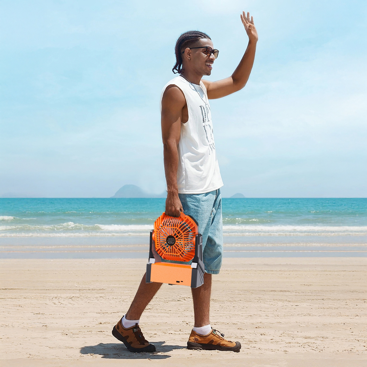 Hombre con ventilador en la playa saludando. Mar y cielo azules.