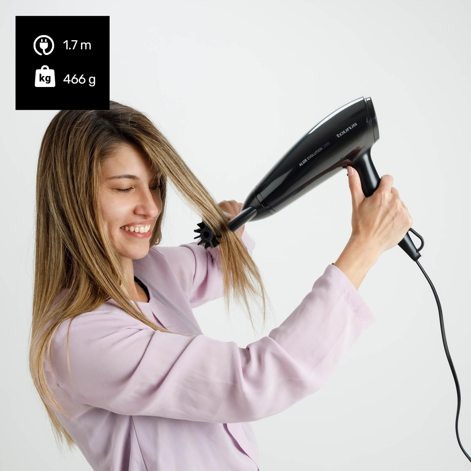 Mujer secándose el pelo rubio con un secador negro y un cepillo.