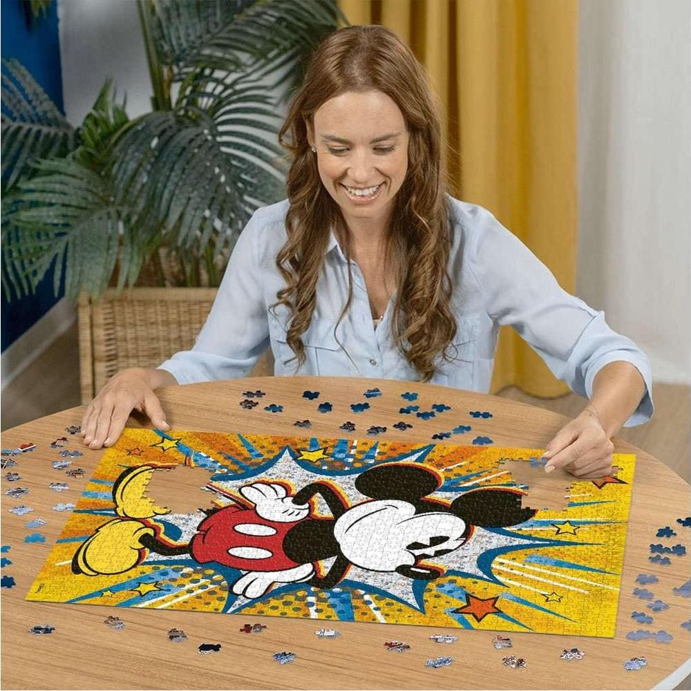 Donna che monta puzzle di Topolino. Molti pezzi sparsi.