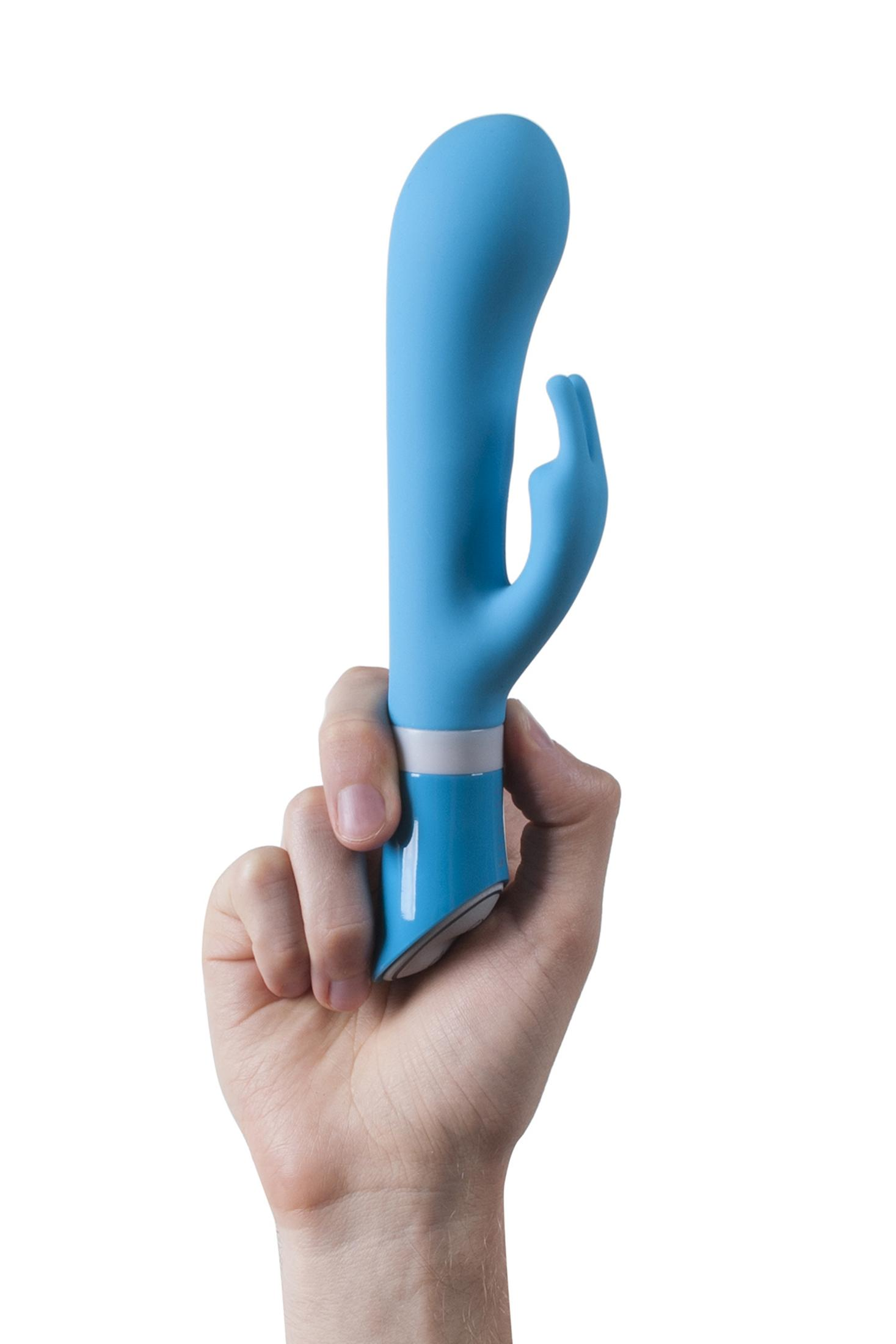 Una mano sostiene un vibrador azul con un anillo blanco.