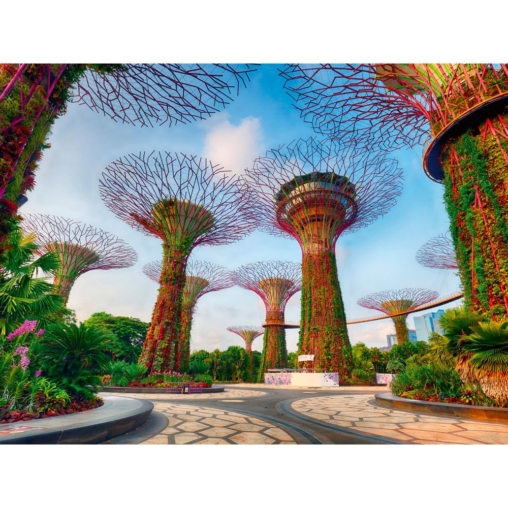 Strutture futuristiche simili ad alberi coperte di piante e illuminate di viola, contro cielo azzurro.