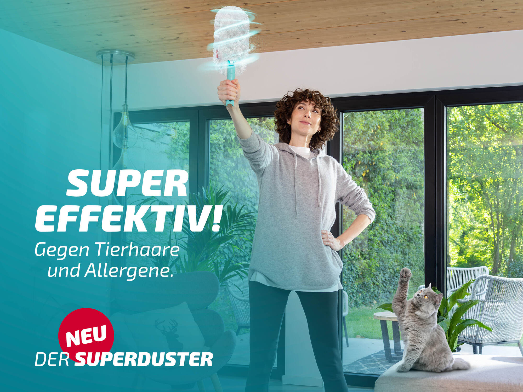 Frau mit Staubwedel und Katze im Raum mit großen Fenstern.