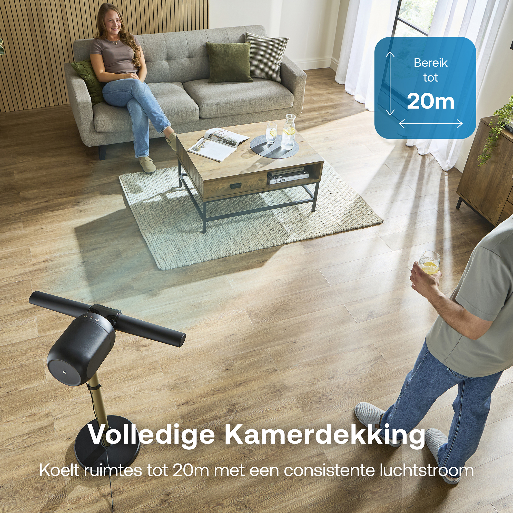 Een ventilator koelt een kamer met een vrouw op de bank en een man met een drankje.