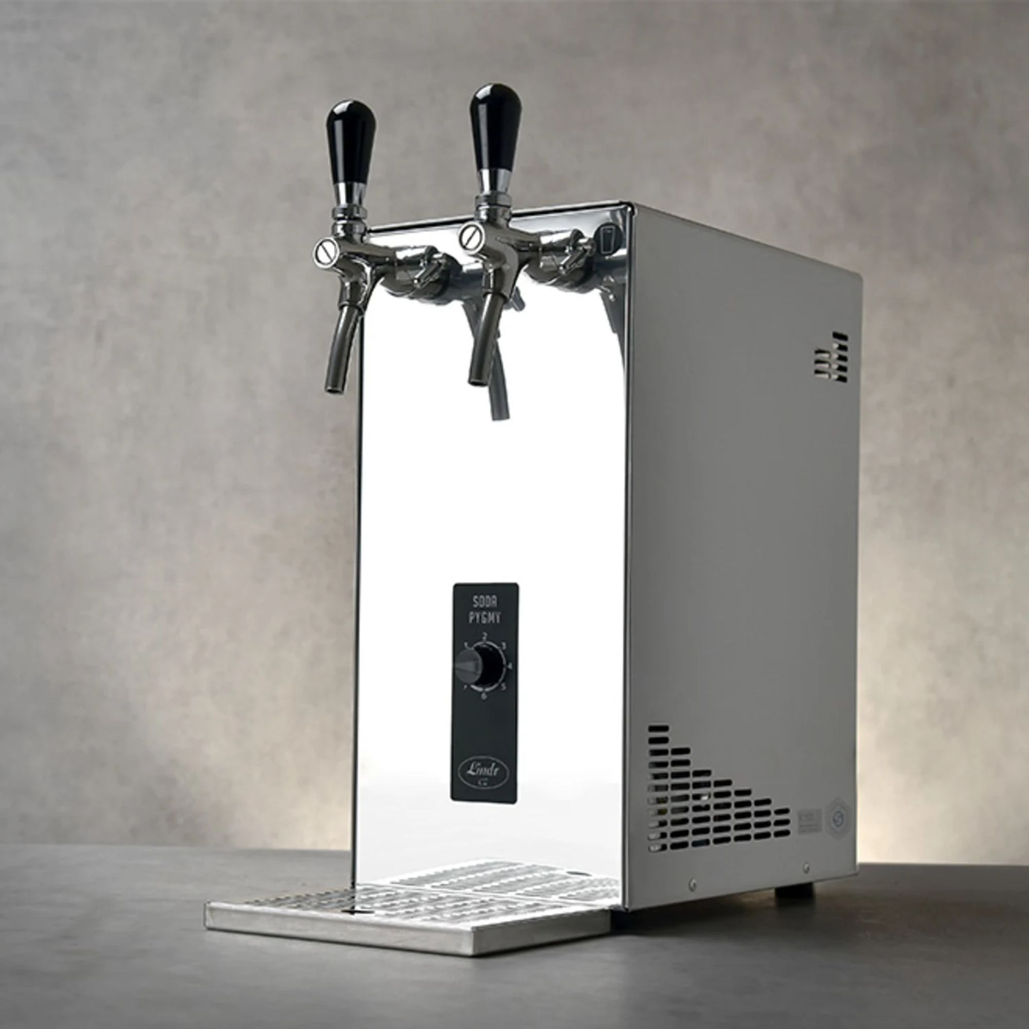 A polished beer dispenser with two taps stands on a table.
