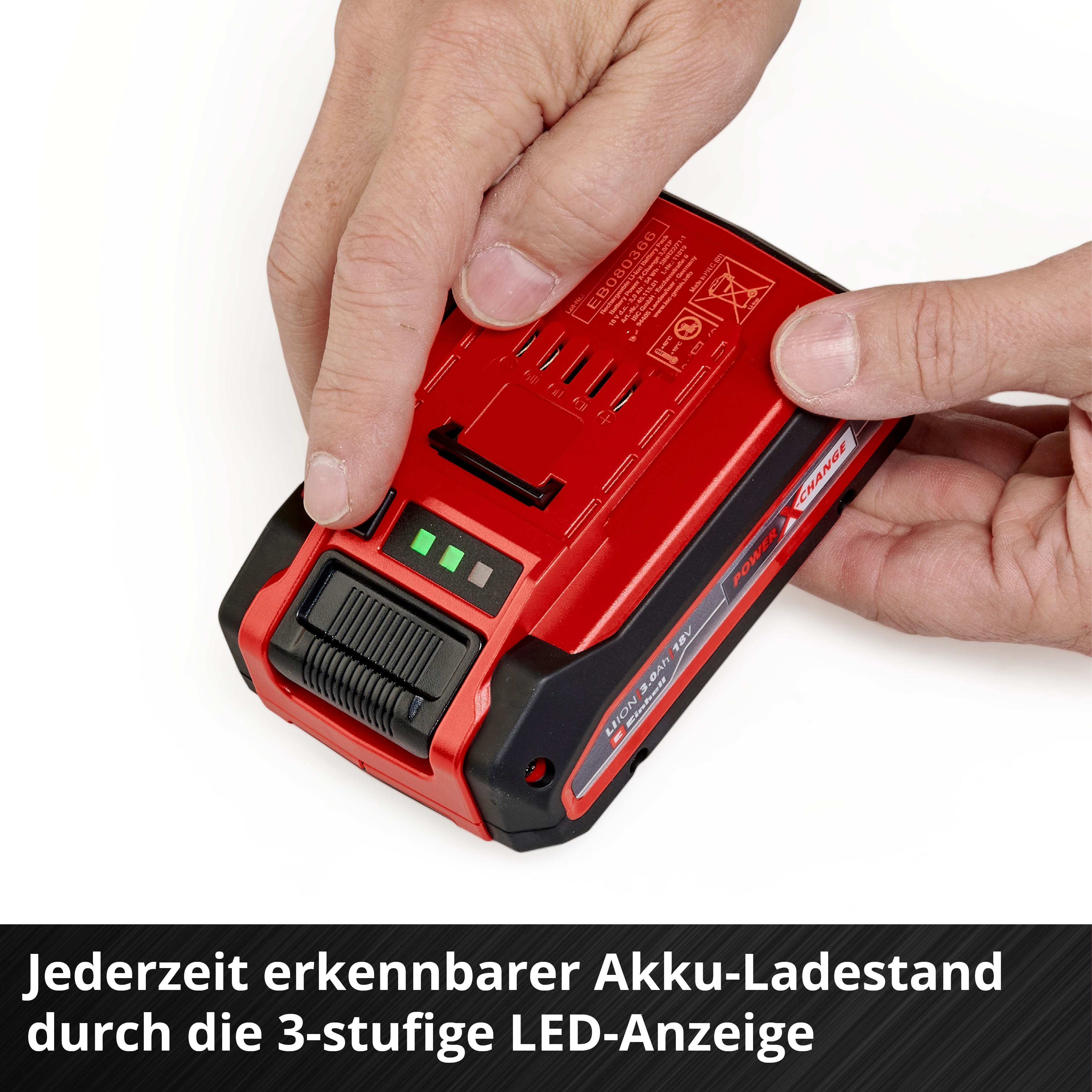 Batteria rossa con display a LED tenuta dalle mani. Livello di carica visibile.