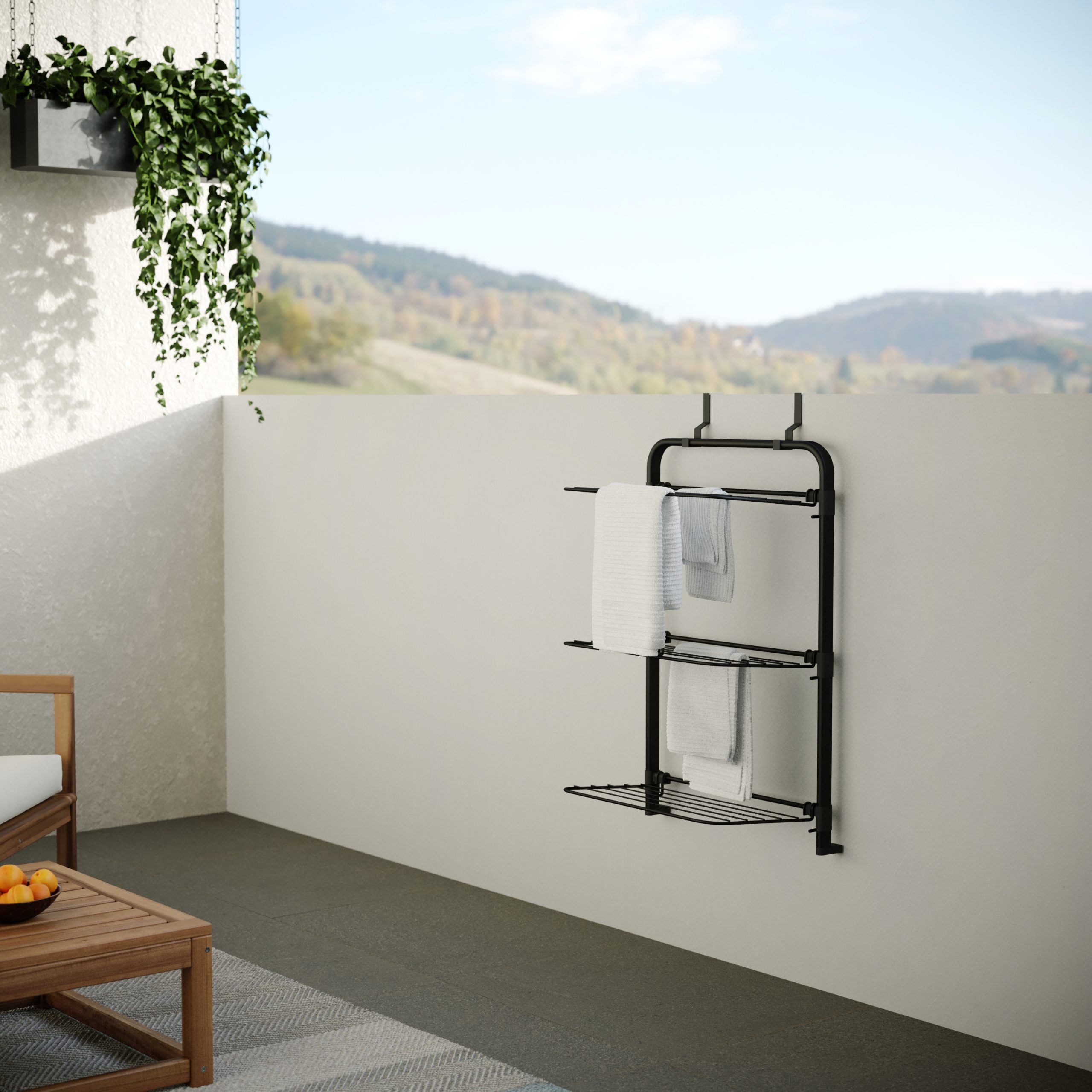 Un porte-serviettes noir avec deux serviettes sur un mur, avec une plante.