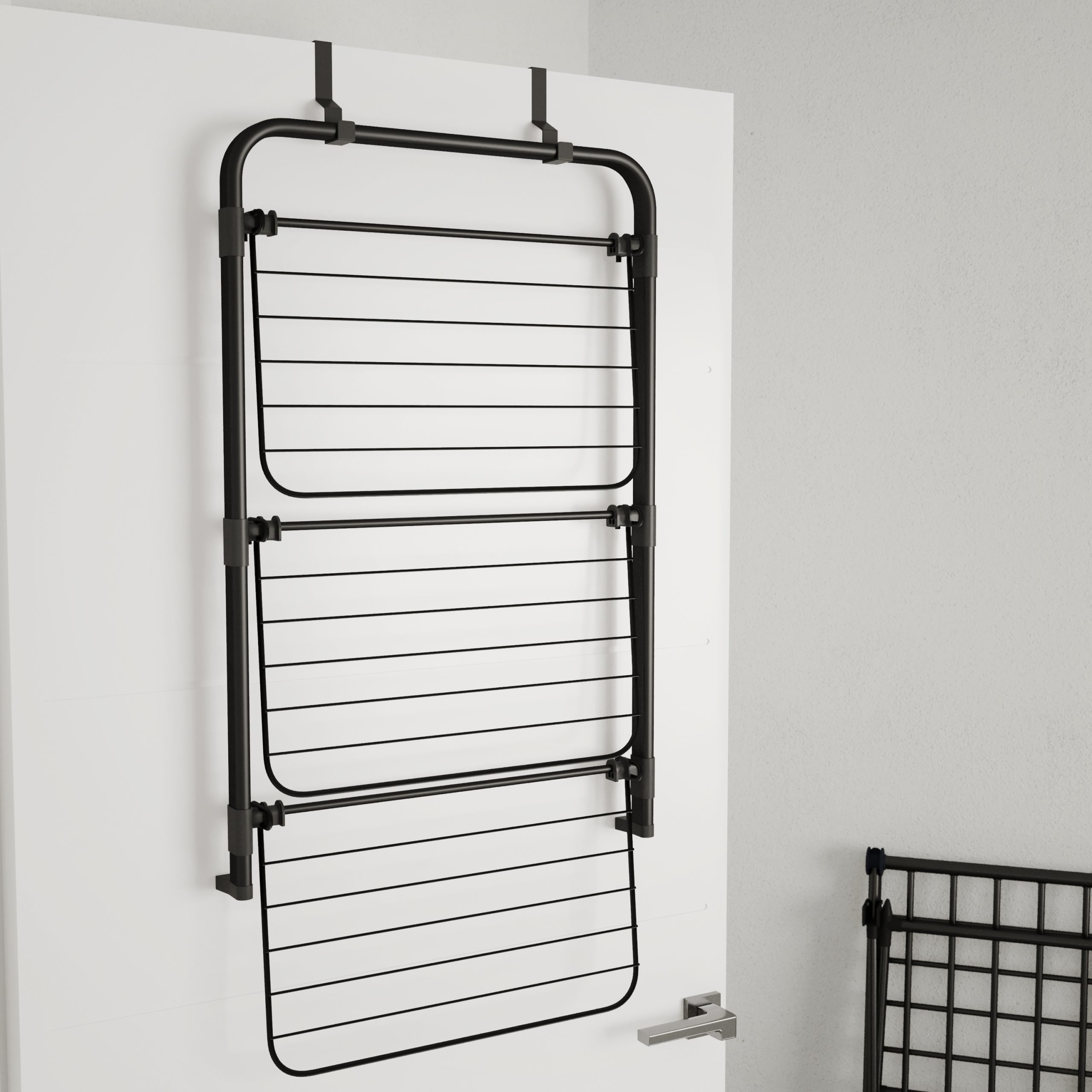Un étendoir noir à suspendre au-dessus de la porte est accroché à une porte blanche avec une poignée argentée.